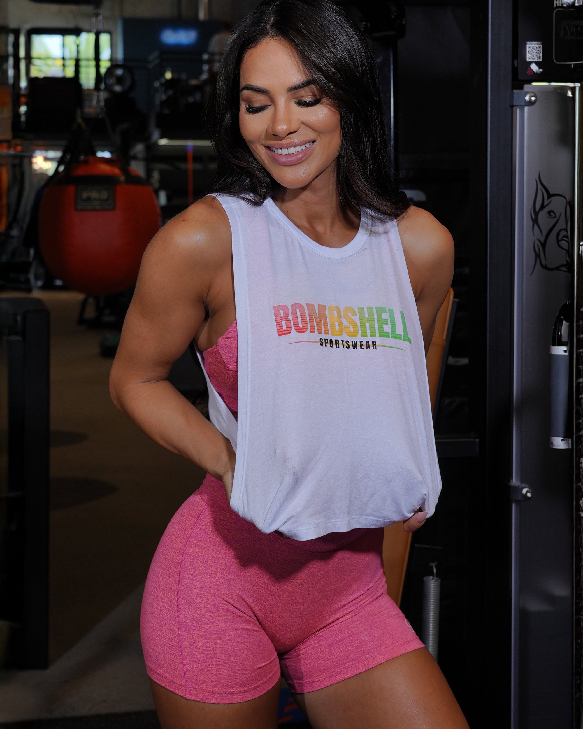 frontal perspective of a model at a gym wearing the white bombshell tee