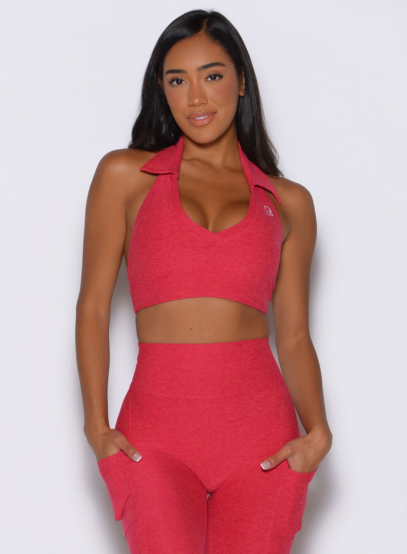front view of a model with both hands inside the pockets of the leggings wearing the Ace Active Top in Victory Ruby color
