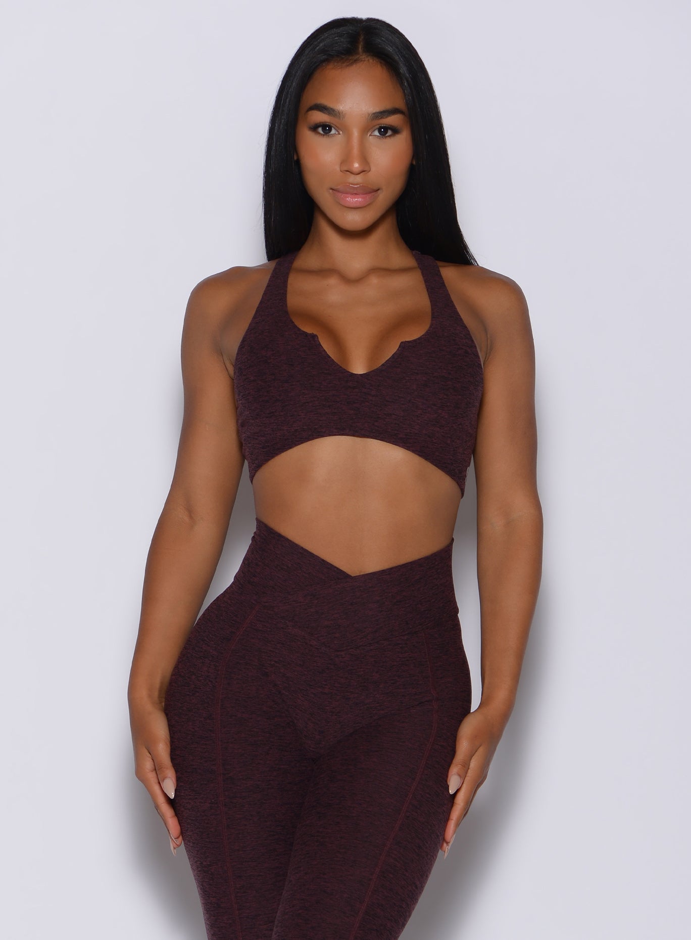 Front profile view of a model wearing our ace sports bra in port color and a matching leggings