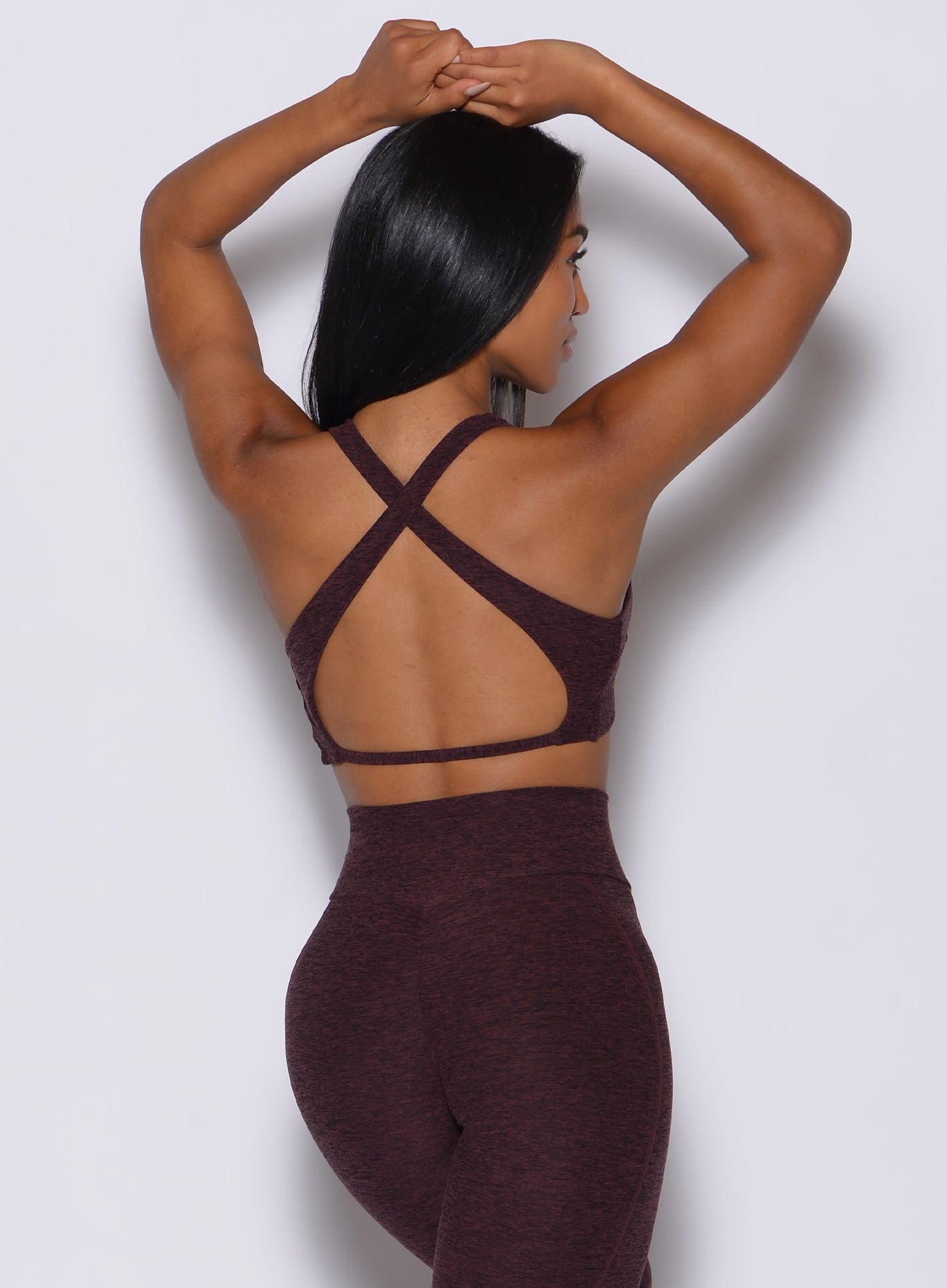 Back profile view of a model in our ace sports bra in port color and a matching leggings