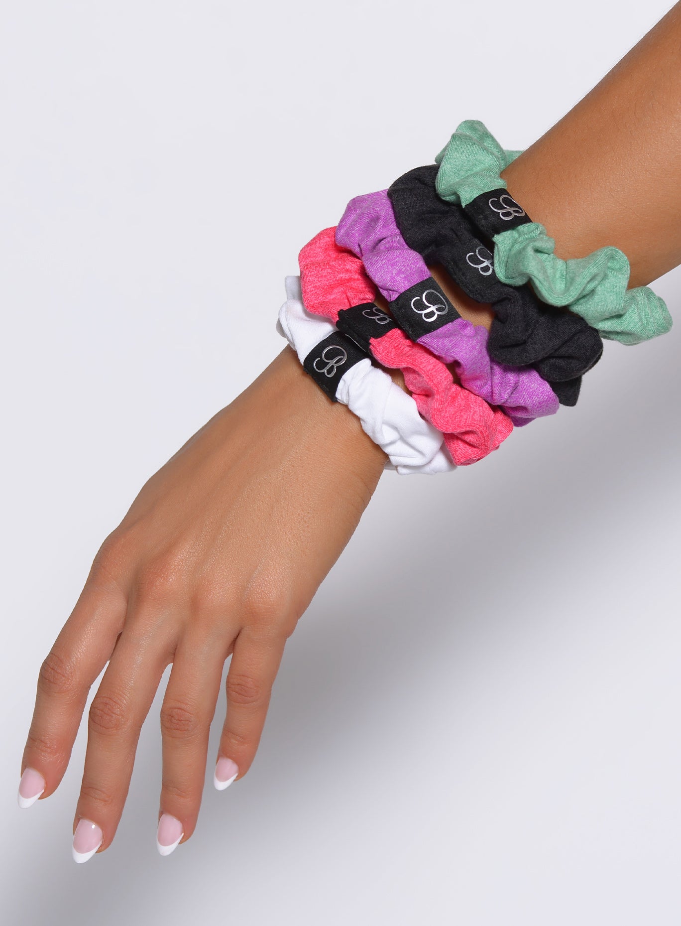 Heathered black B Scrunchie on a wrist, a stretchy and soft athletic hair accessory for gym workouts.