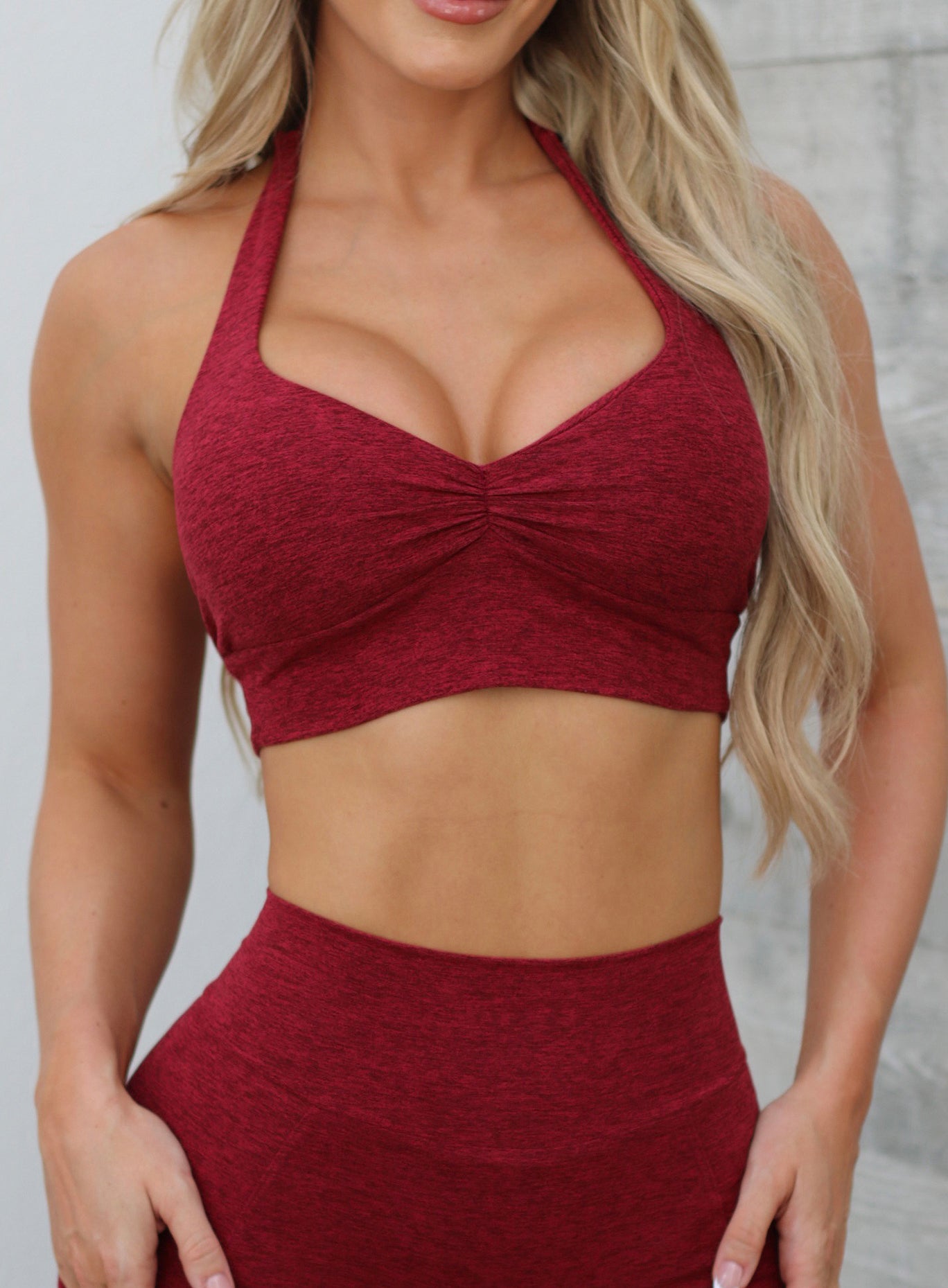 Front close up profile view of a model in our V Back Leggings in garnet red along with the matching bra