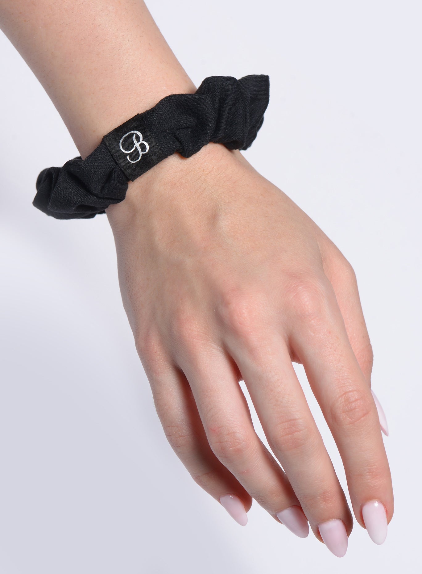 Versatile black B Scrunchie on wrist; premium stretchy fabric for a secure, stylish gym hairstyle.