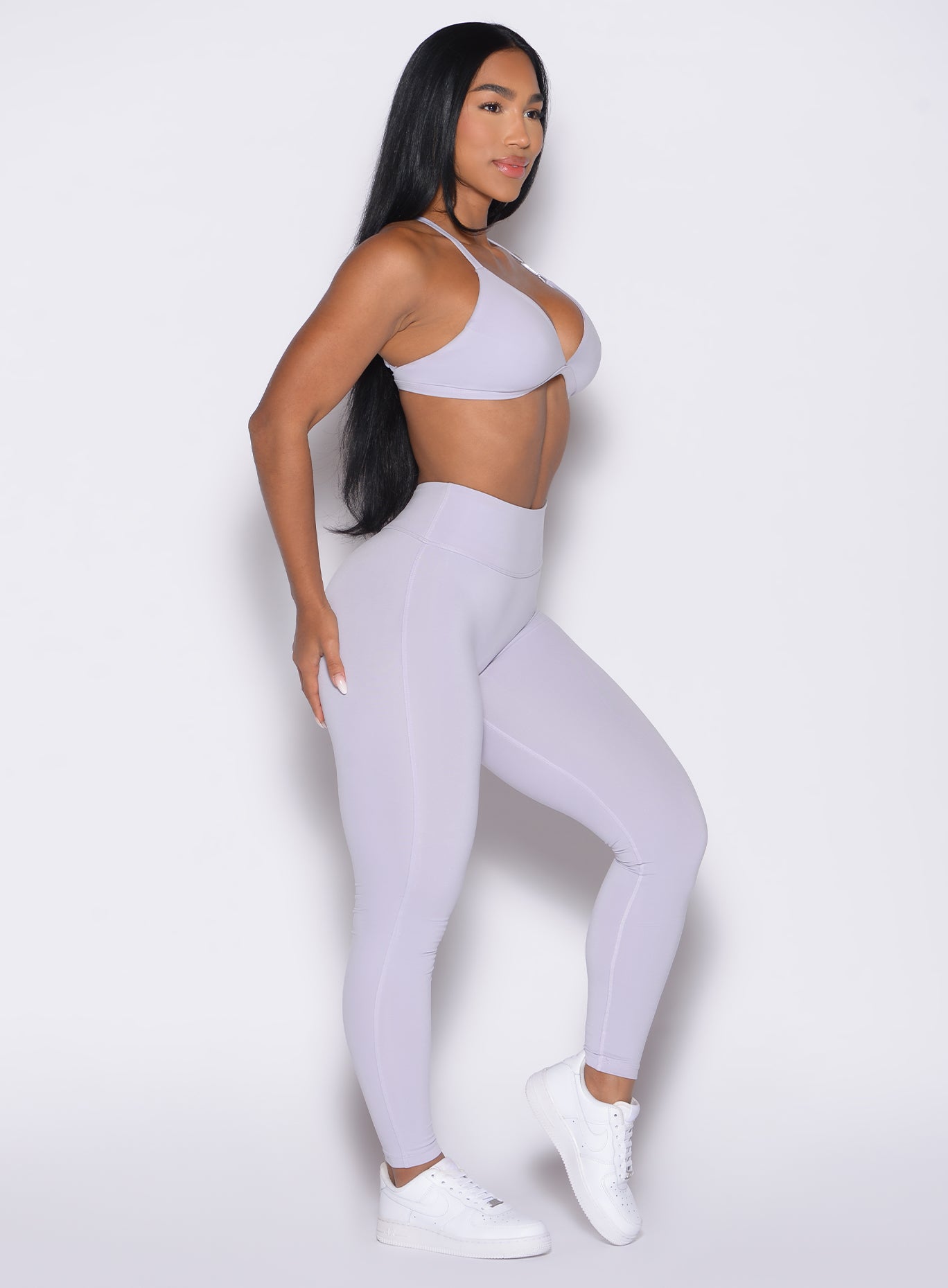 right side profile view of a model wearing the Bombshell Bunny Leggings in Galactic Lilac color paired with the matching bra