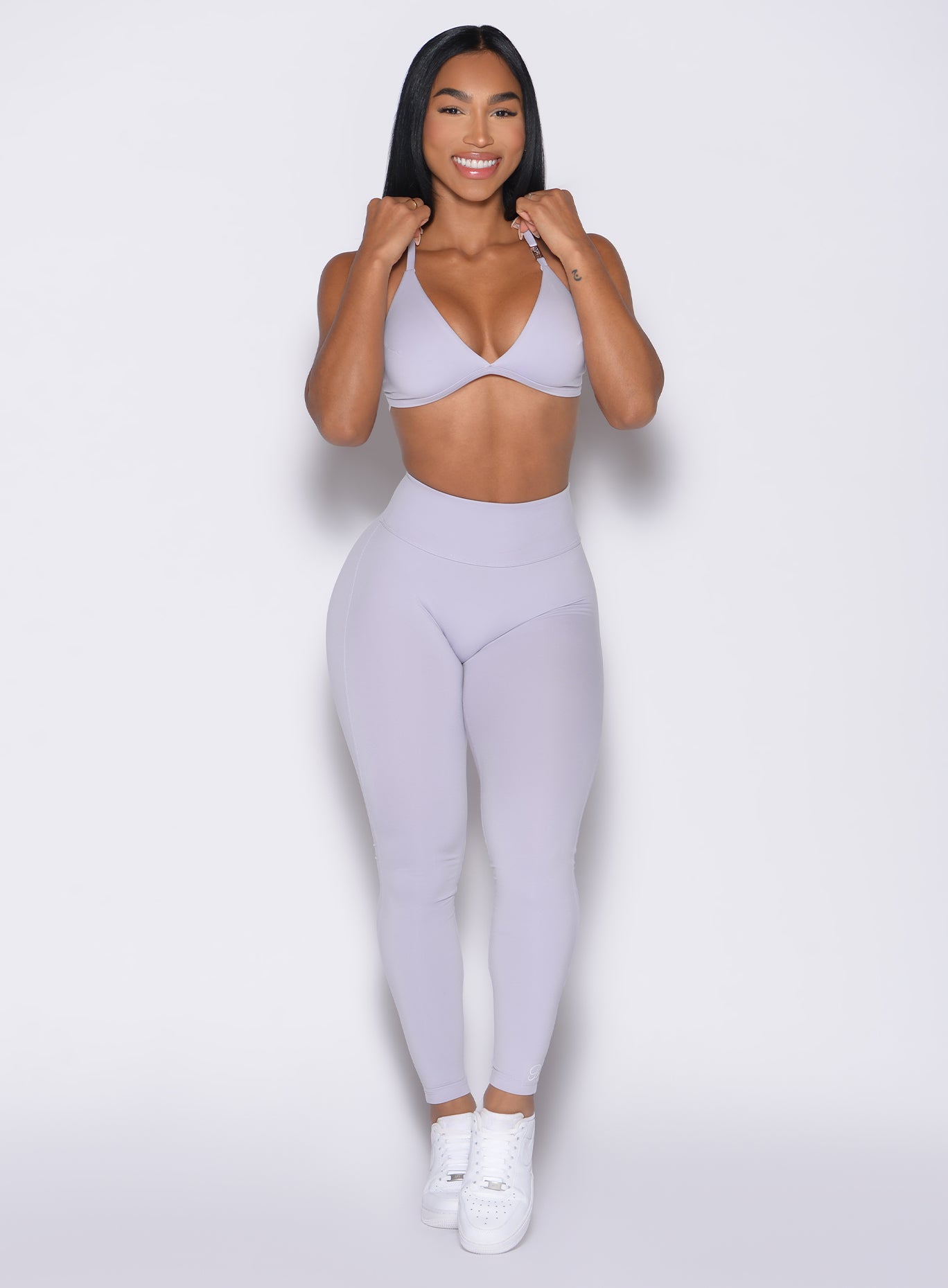 front profile view of a model with both hands on her bra straps wearing the Bombshell Bunny Leggings in Galactic Lilac color