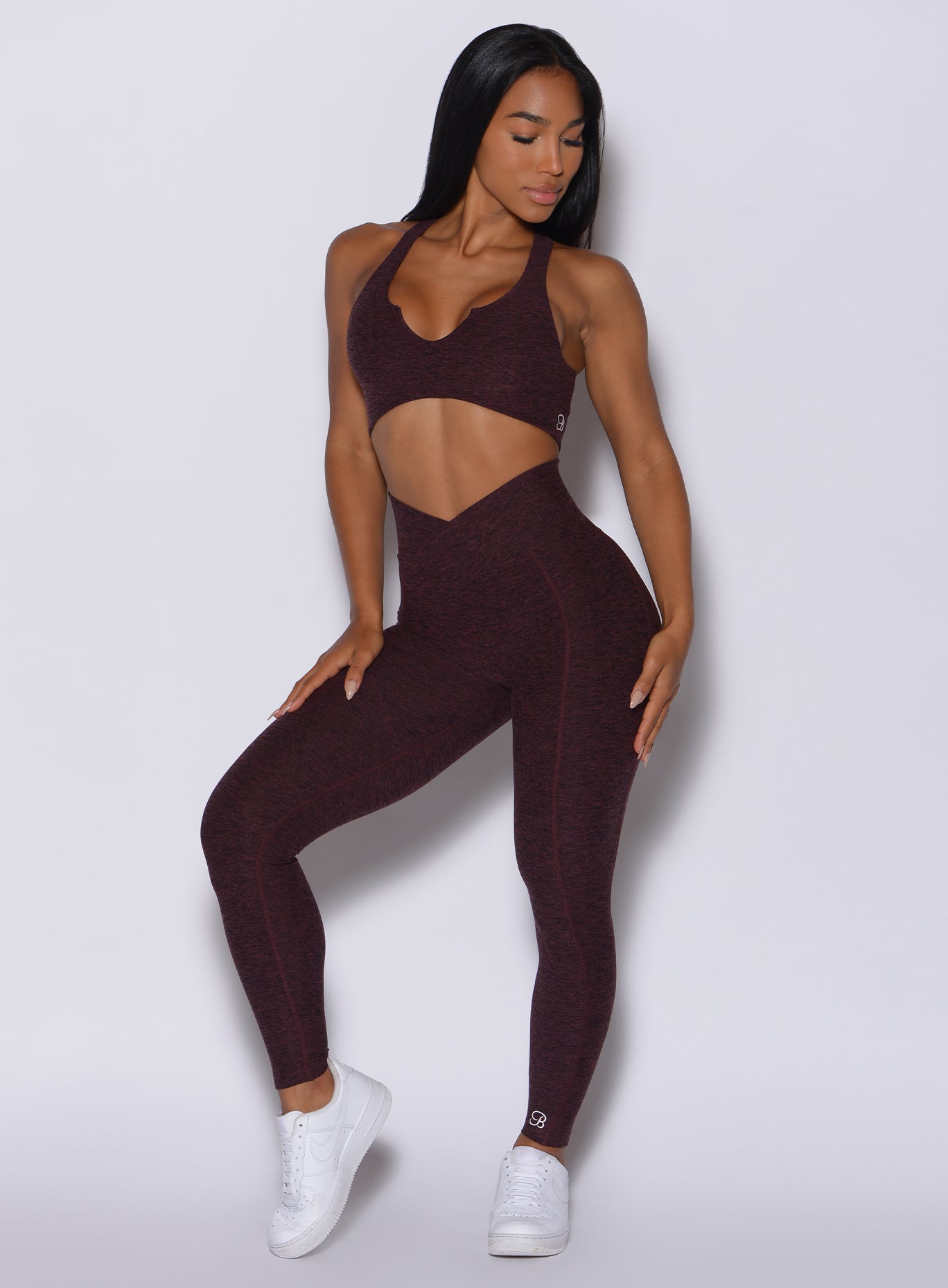 Front profile view of a model in our Brazilian Contour Leggings in port color and a matching ace sports bra