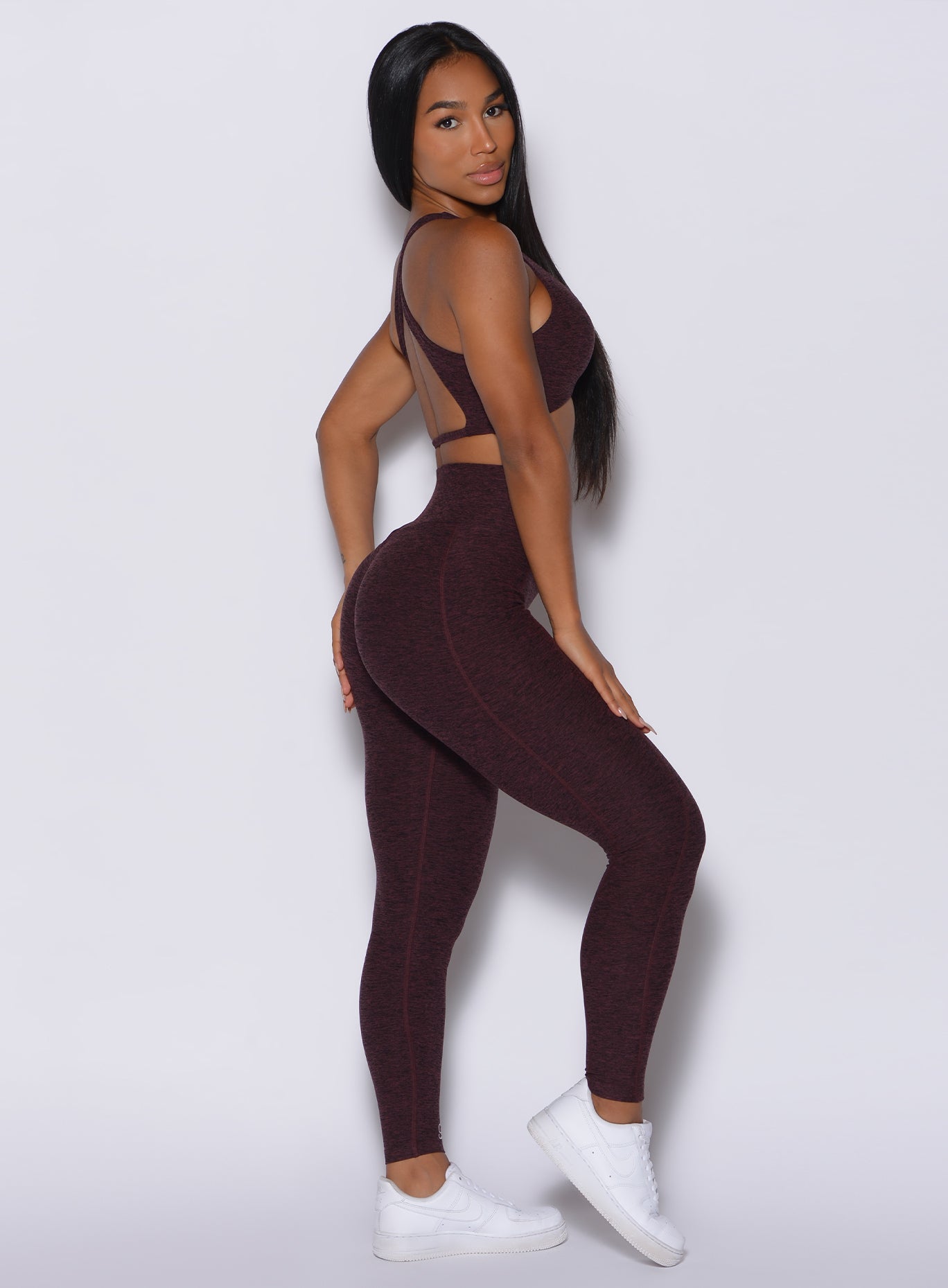 Right side profile view of a model in our Brazilian Contour Leggings in port color and a matching sports bra