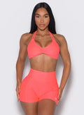 front profile view of a model wearing our butterfly sports bra in Neon Apricot Pink color along with the matching shorts