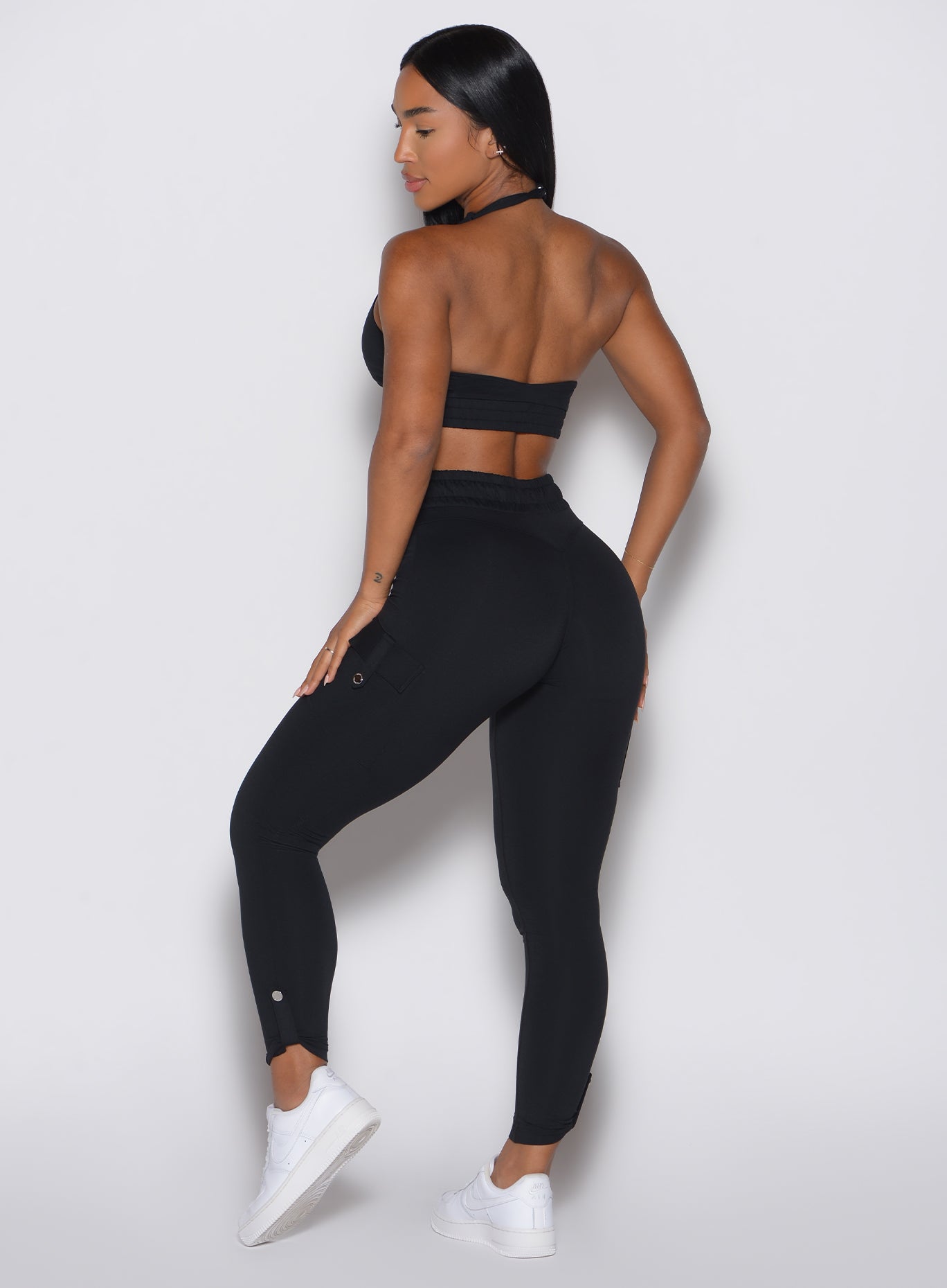 back profile view of a model wearing the Cargo Edge Leggings in Black color paired with the matching bra