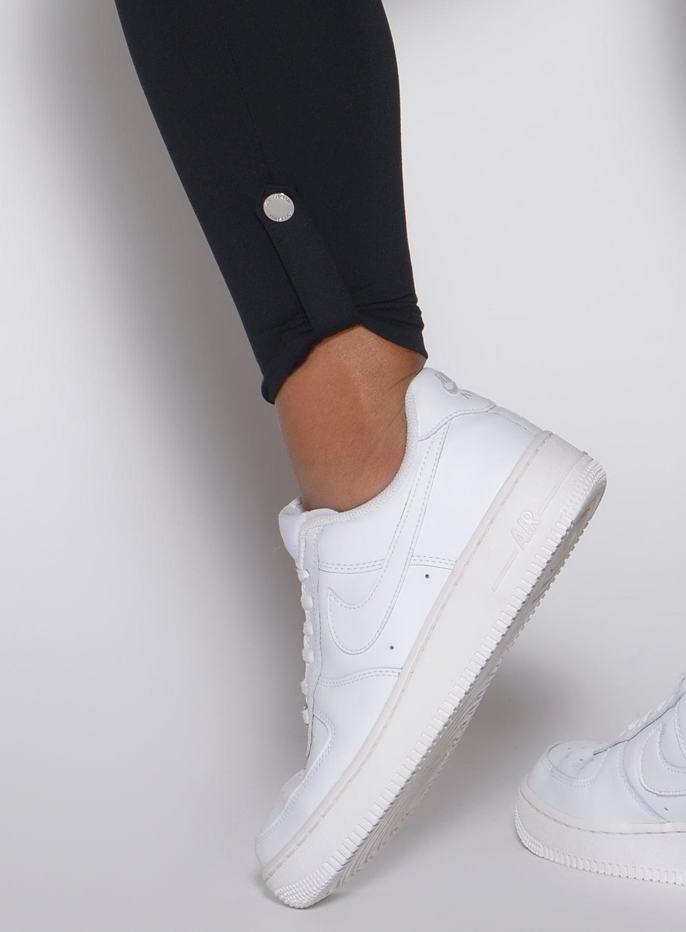 Close-up view of the functional ankle snap detail on black Cargo Edge Leggings for gym workouts.