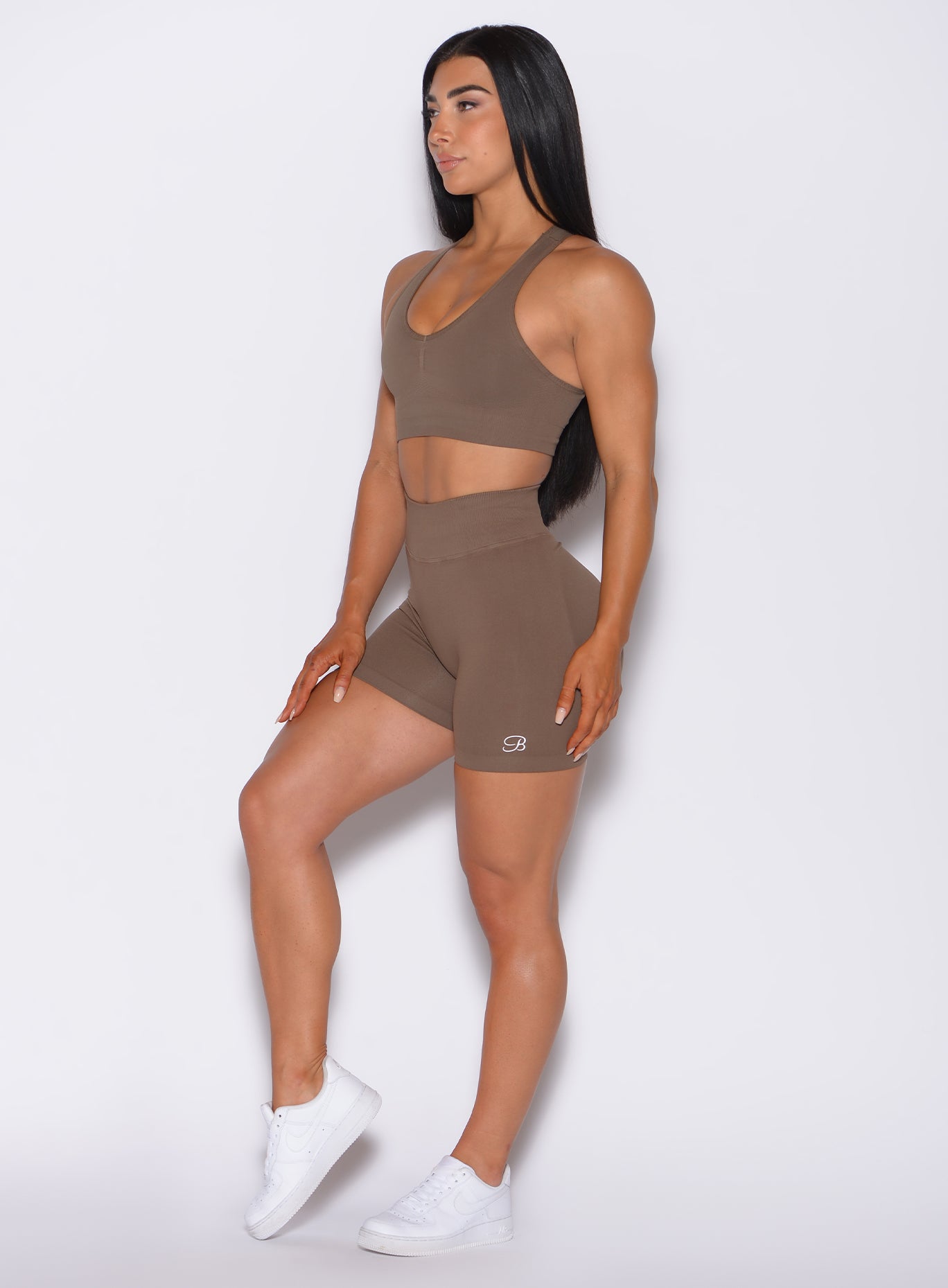 left side profile view of a model angled left wearing our Cheeky Seamless Shorts in beachwood color, along with a matching bra