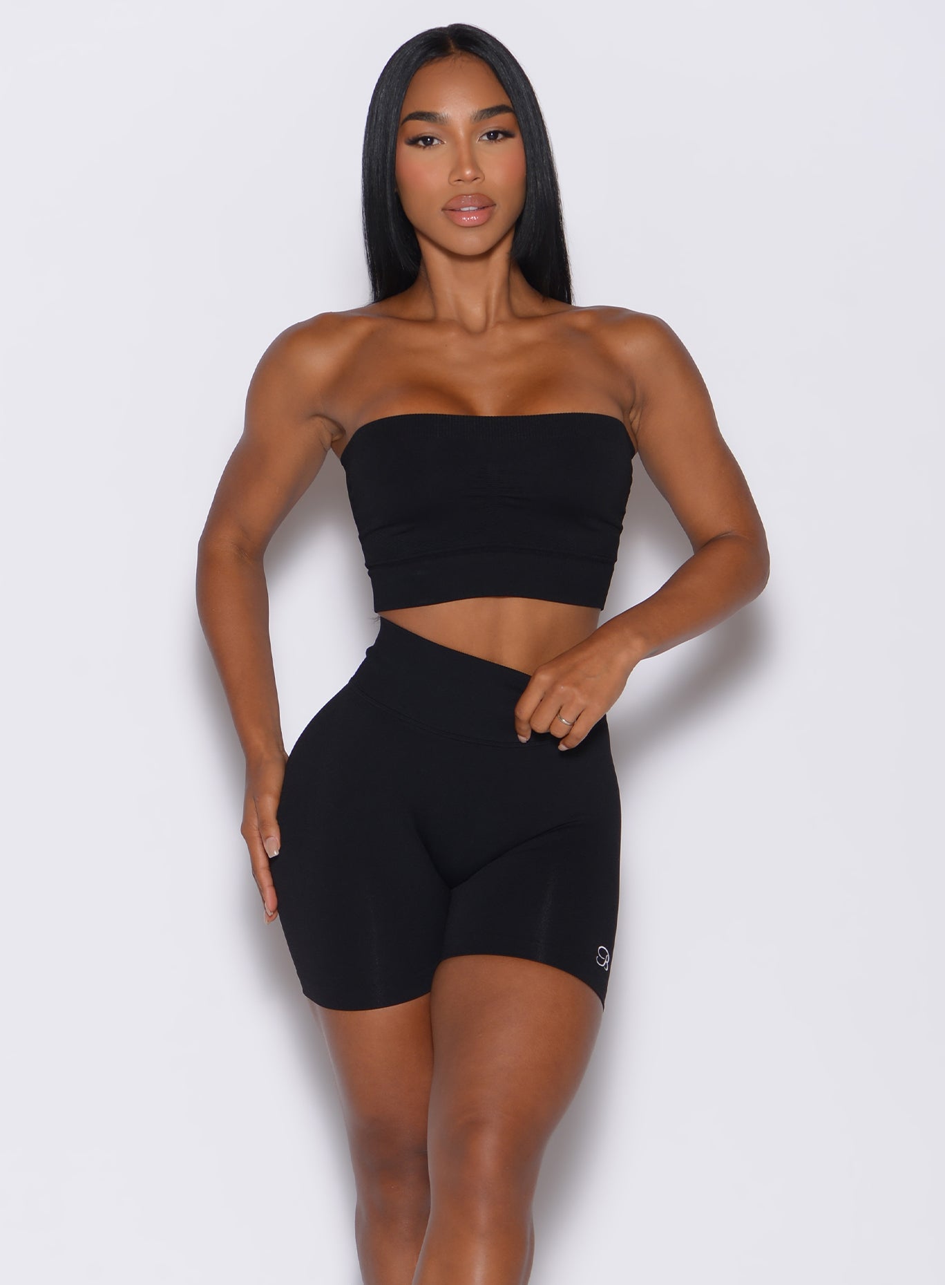 front profile picture of a model facing forward, wearing our black seamless bandeau along with the matching shorts