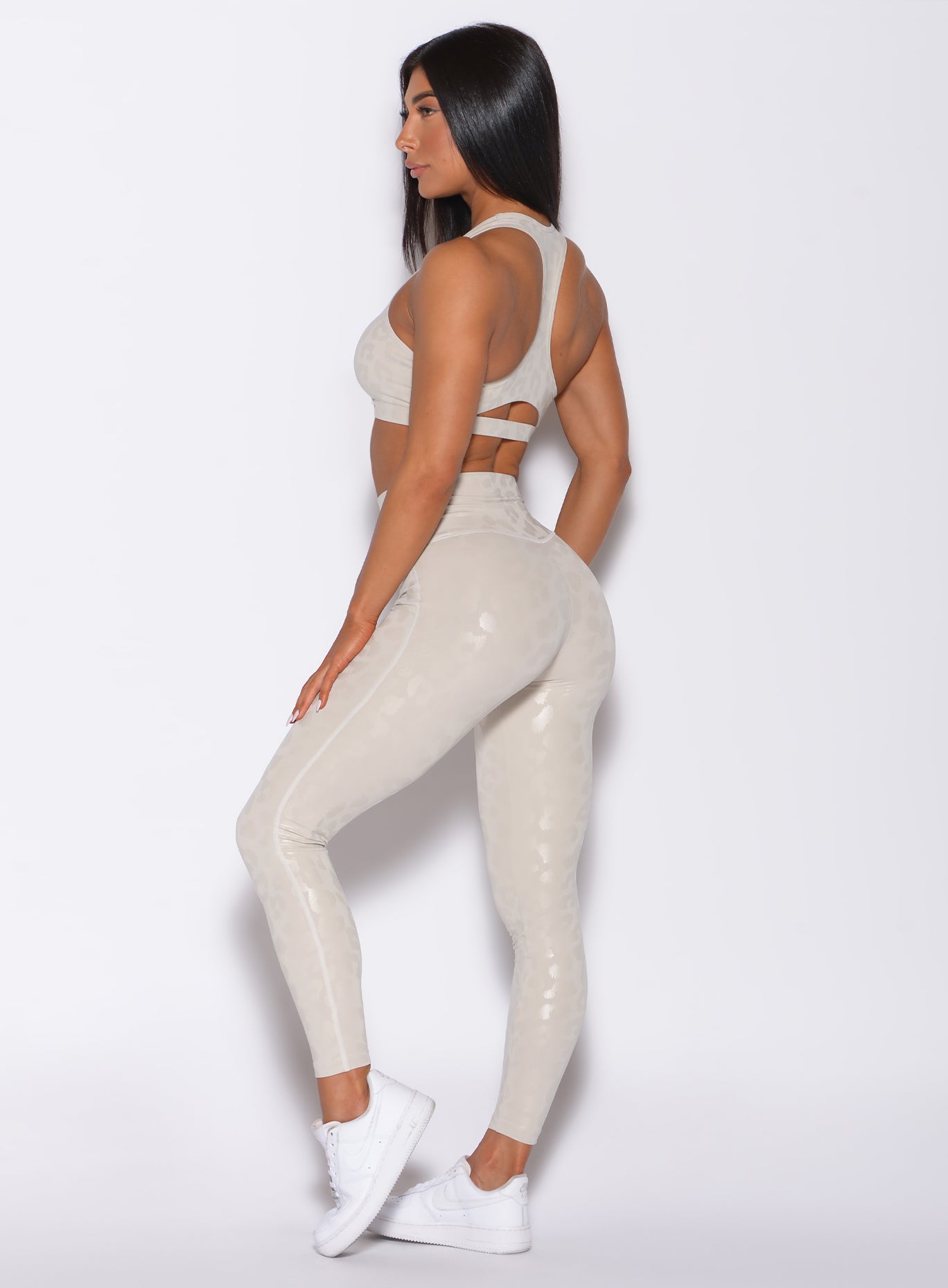 Left side profile view of a model wearing our shine leopard leggings in Buff Leopard color along with the matching sports bra