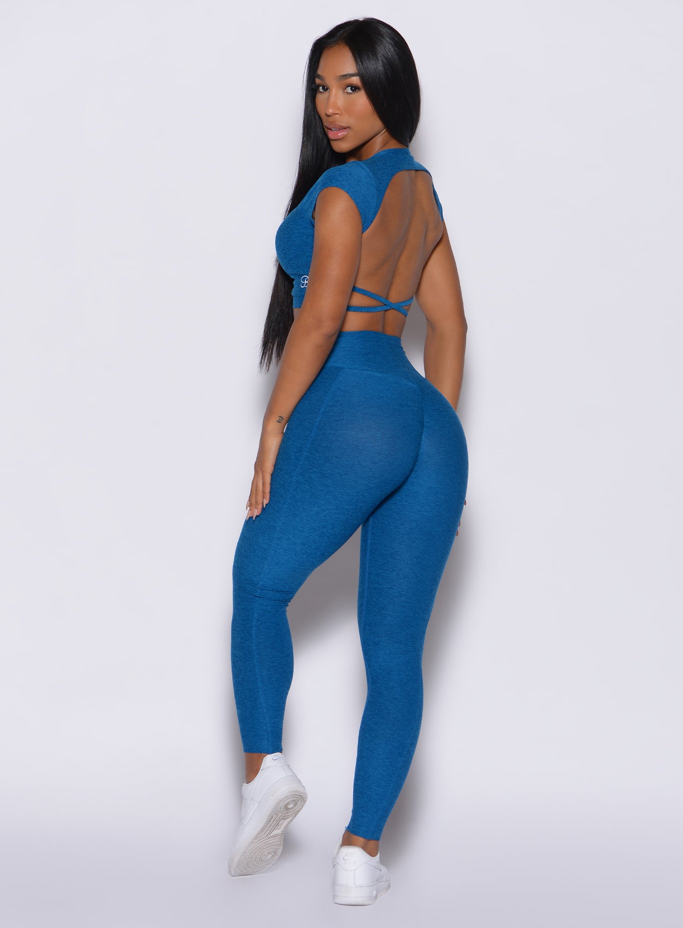 Left side profile view of a model in our cloud leggings in azure color and a matching bra