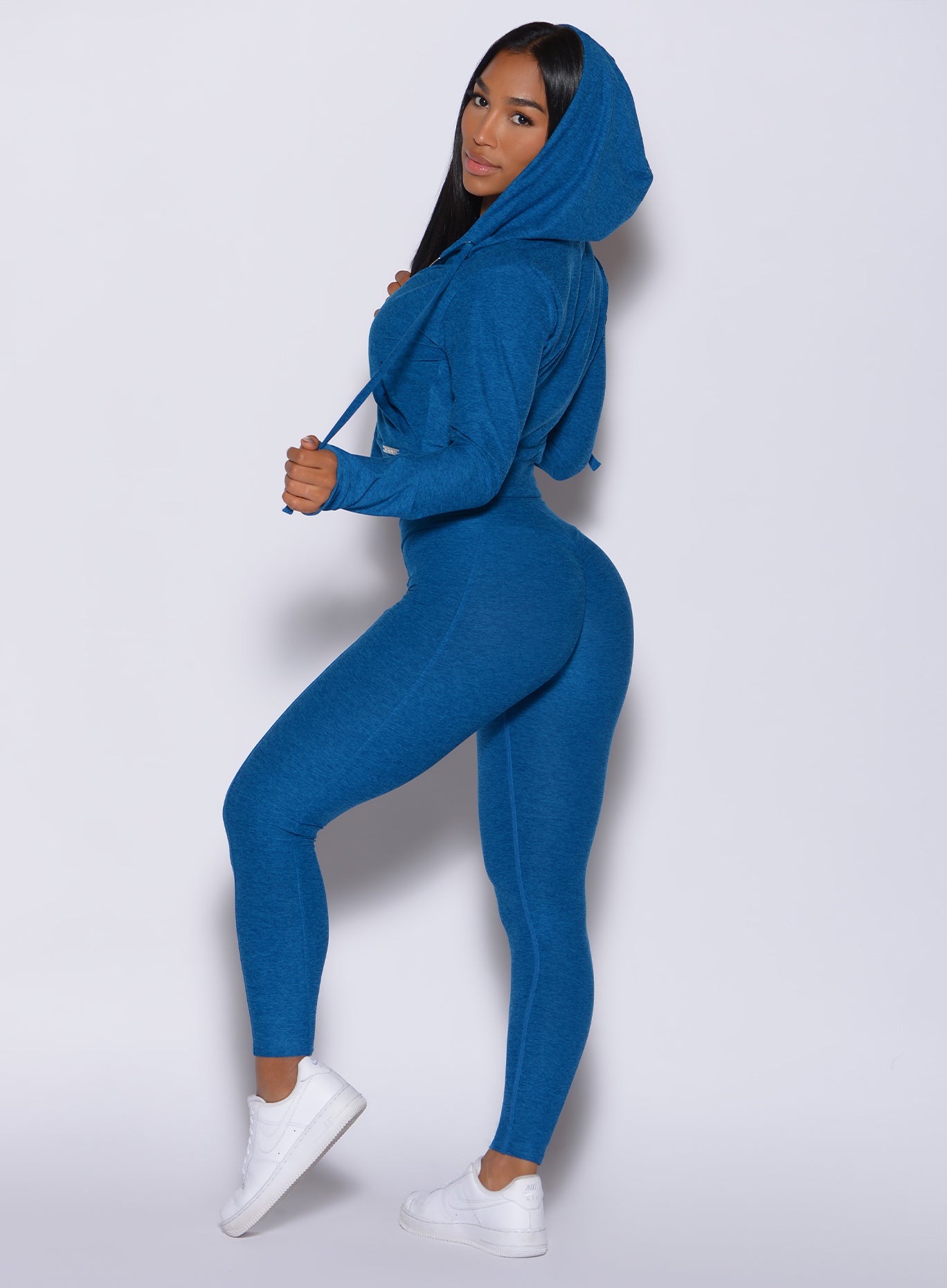 Left side profile view of a model facing to her left wearing our cloud leggings in azure color and a matching jacket