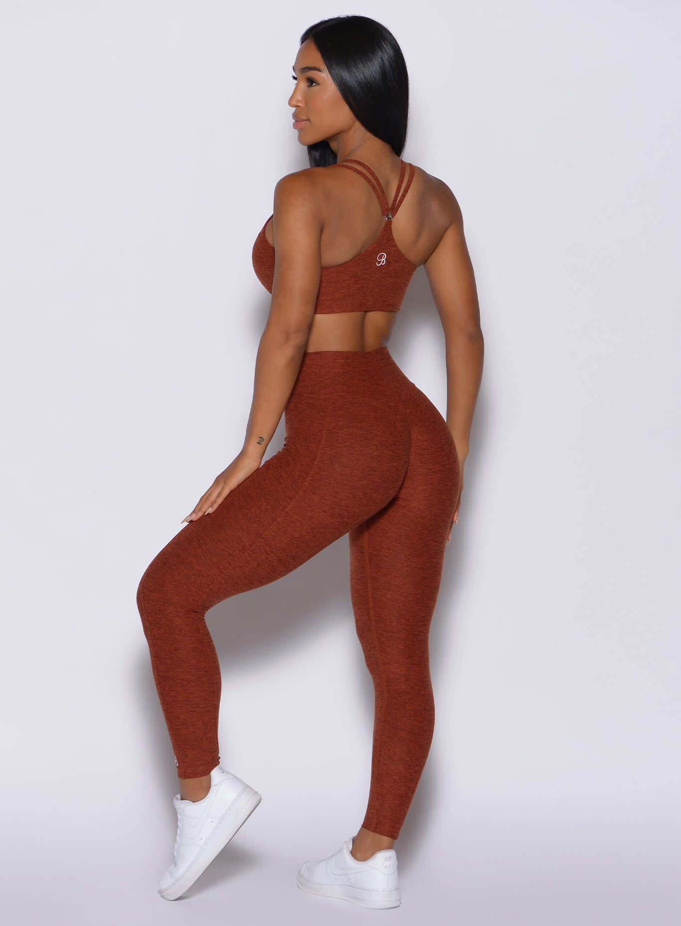 Back profile view of a model facing to her left wearing our cloud leggings in Cinnamon color and a matching bra