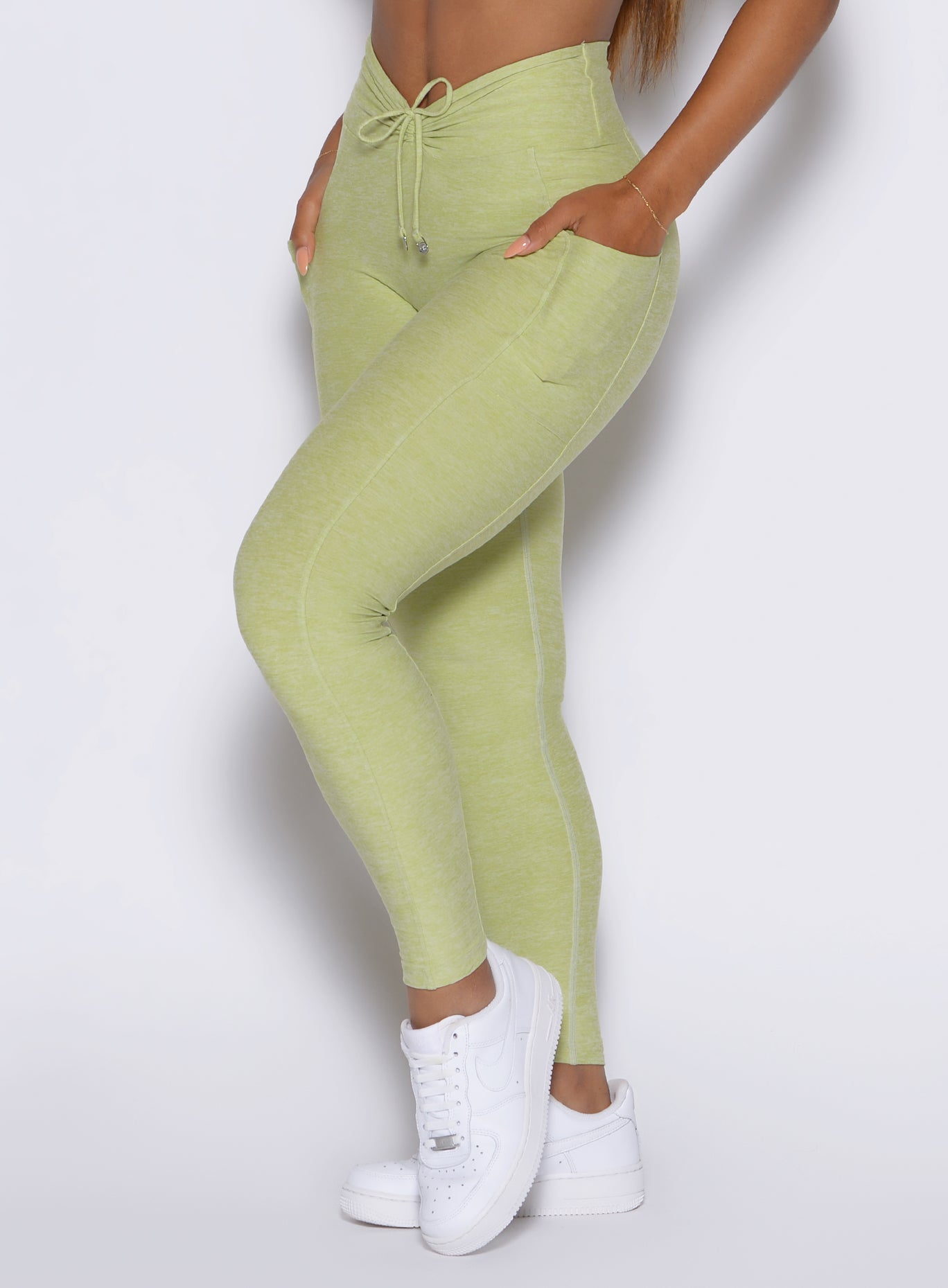 Close-up side view of Serpentine Charm Fit Leggings featuring a cinched V-front and side pockets.