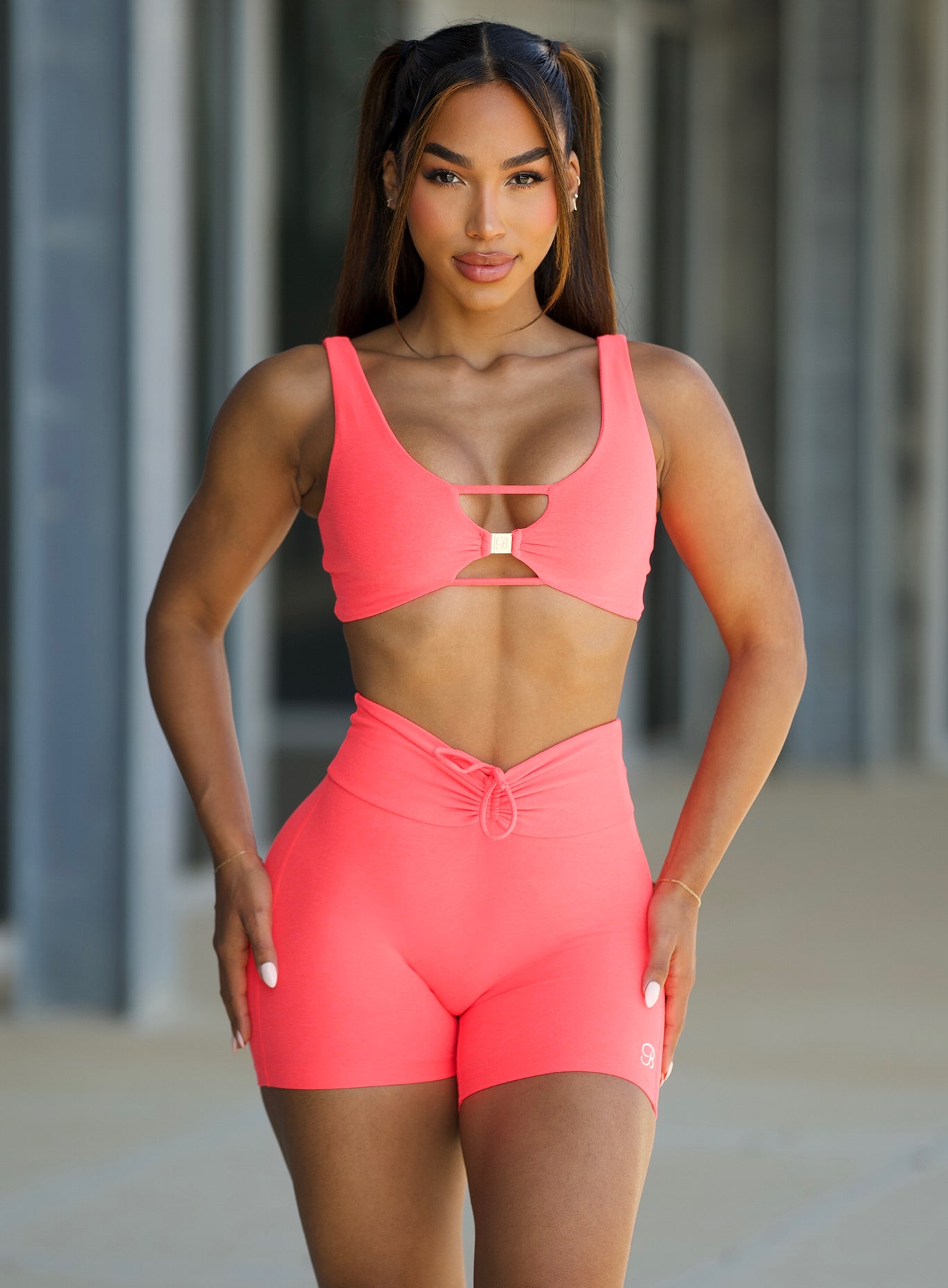 model in outdoors wearing the Curvemax Shorts in Neon Apricot pink color