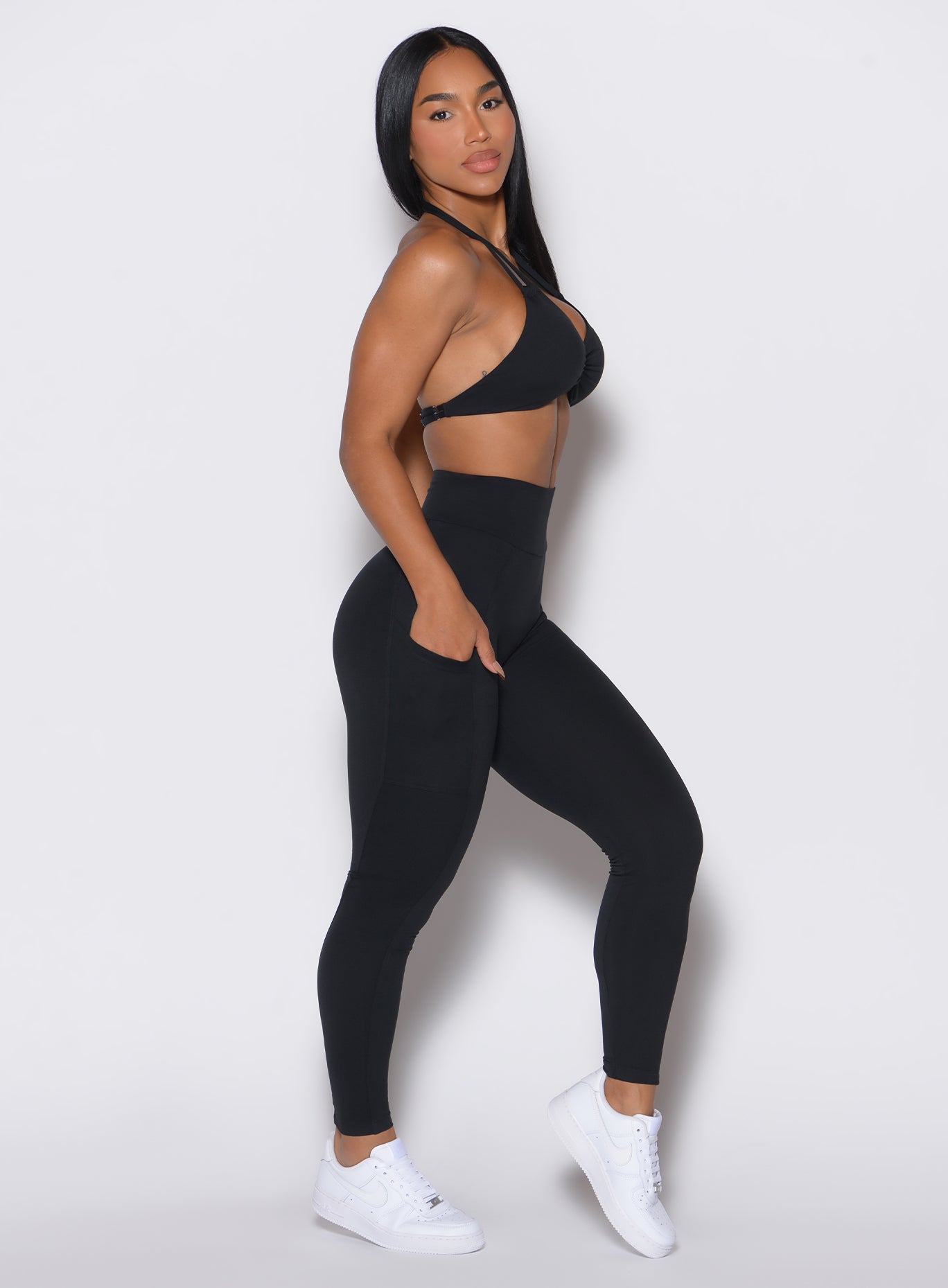 right side profile view of a model facing to her right wearing our black curves leggings along with a matching sports bra