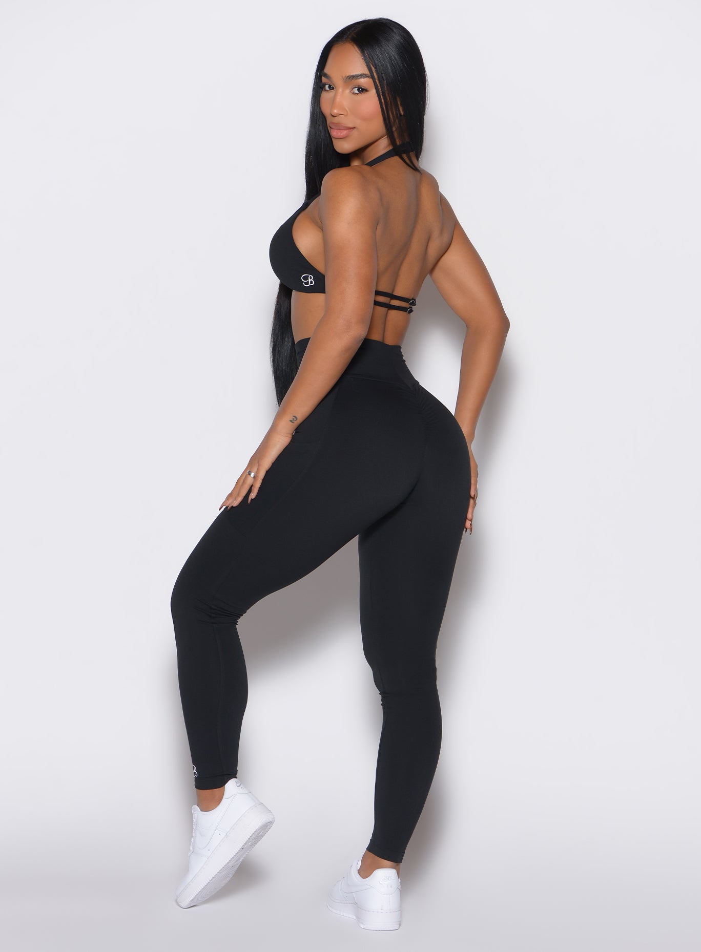 Left side profile picture of a model facing to her left wearing our black curves leggings along with a matching sports bra