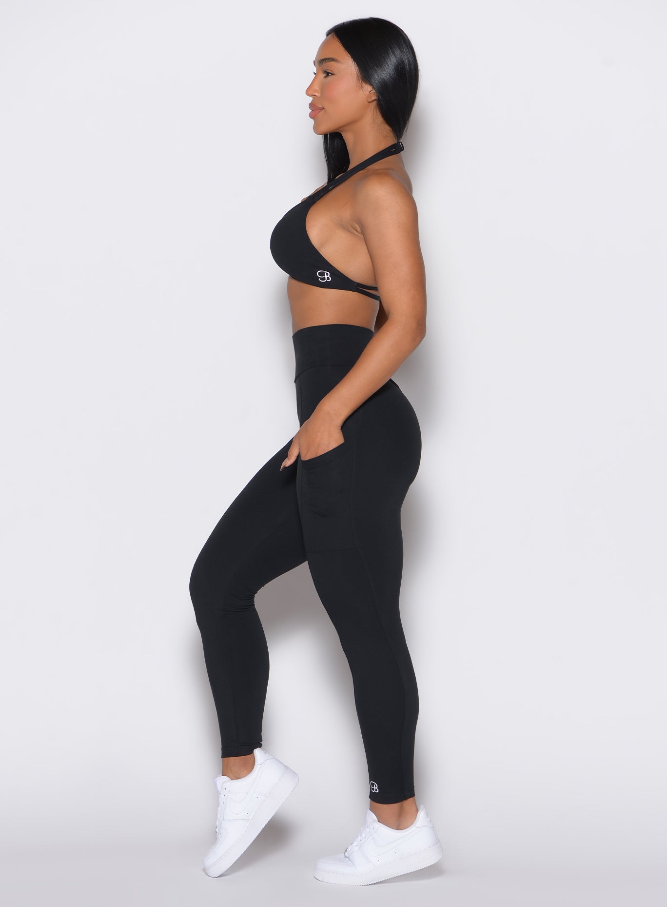 left side profile view of a model facing forward wearing our black curves leggings along with the matching sports bra