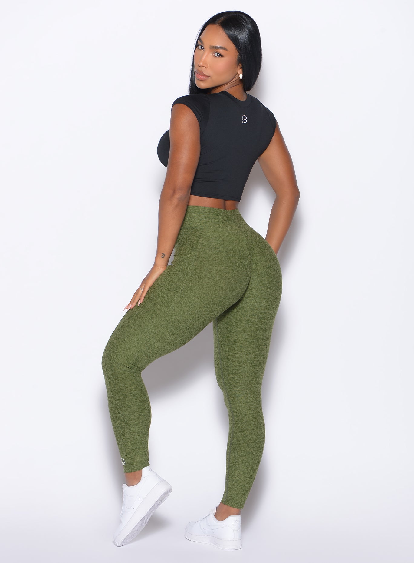 back profile view of a model looking to her back wearing our Flex Long Tee in Black color and the Curves 2.0 Leggings in Juniper color