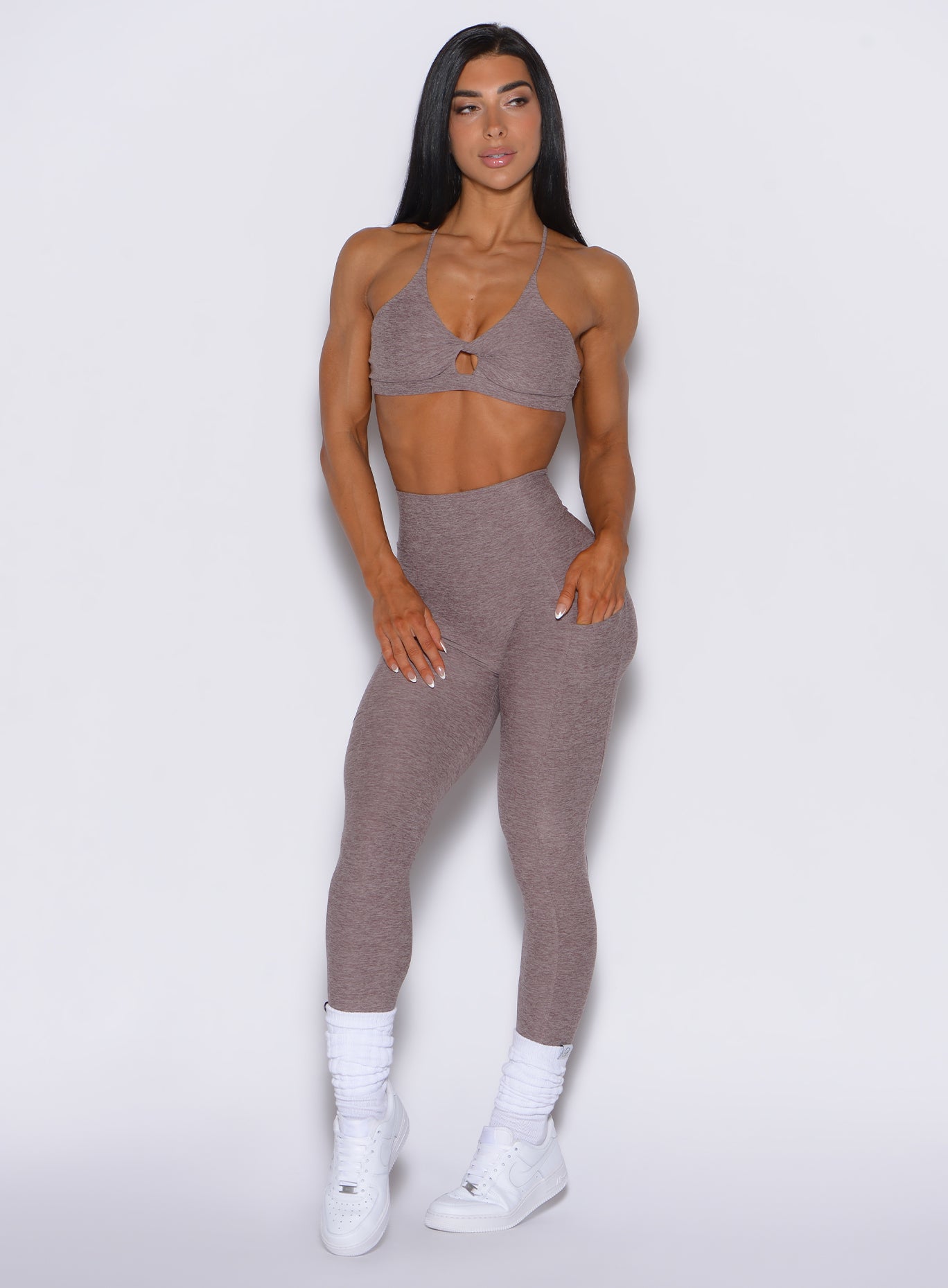 front profile view of a model with her left hand in pocket wearing our curves leggings in london fog color along with the matching bra