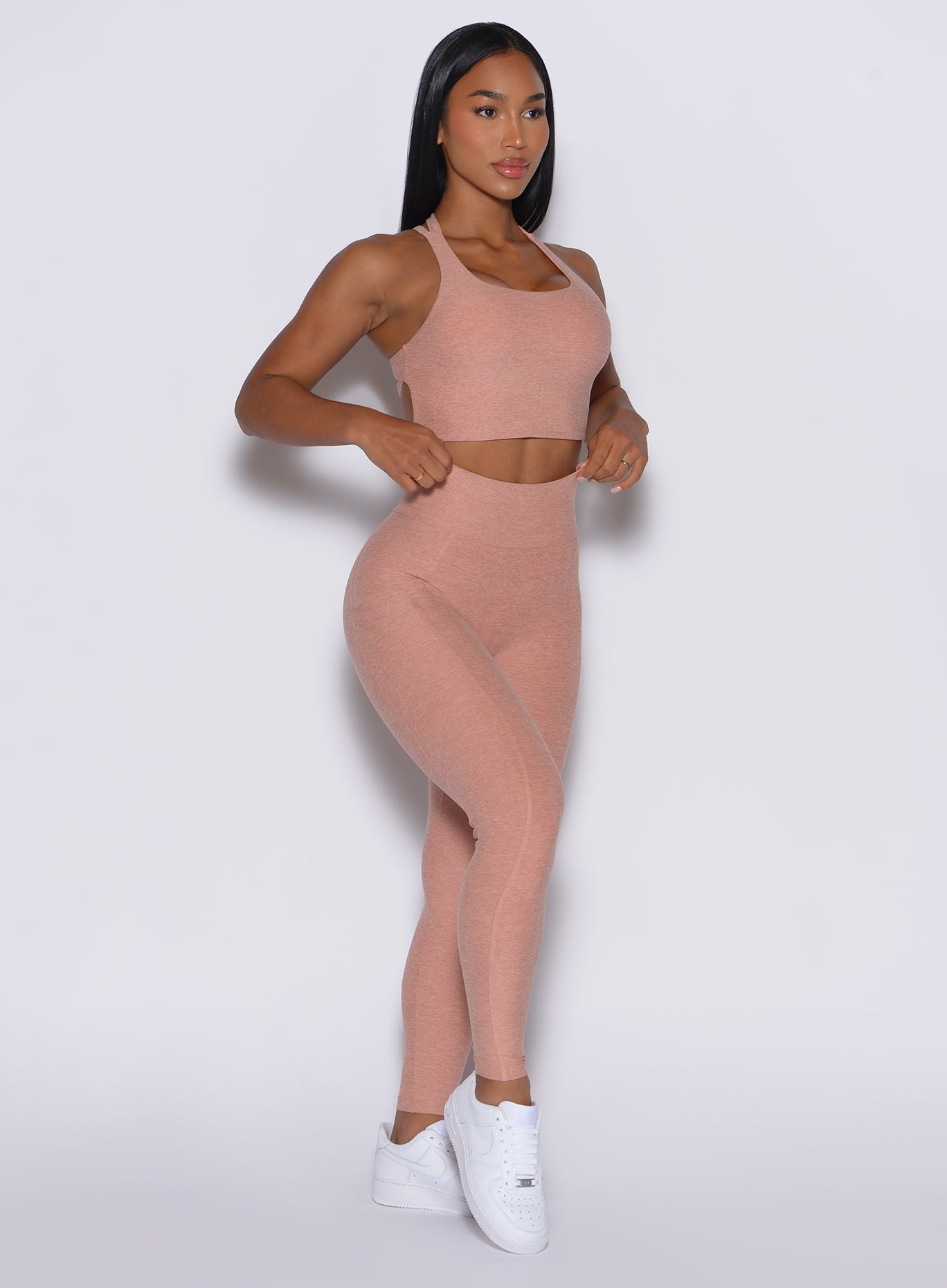 right side profile view of a model angled slightly to her right wearing our Curves leggings in Nude Sand color, paired with the matching sports bra.