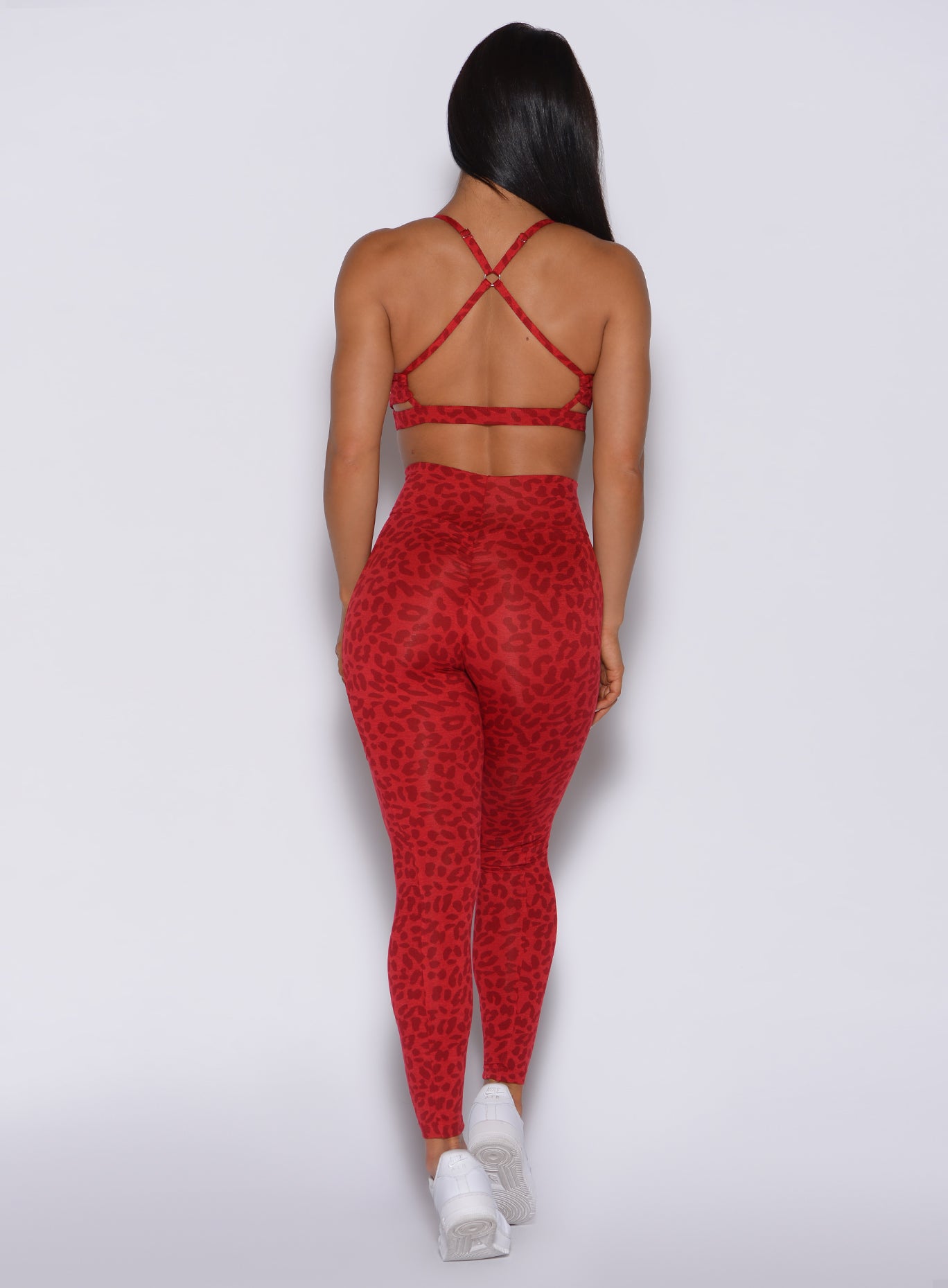 Back profile view of a model in our curves leggings in red cheetah color and a matching sports bra