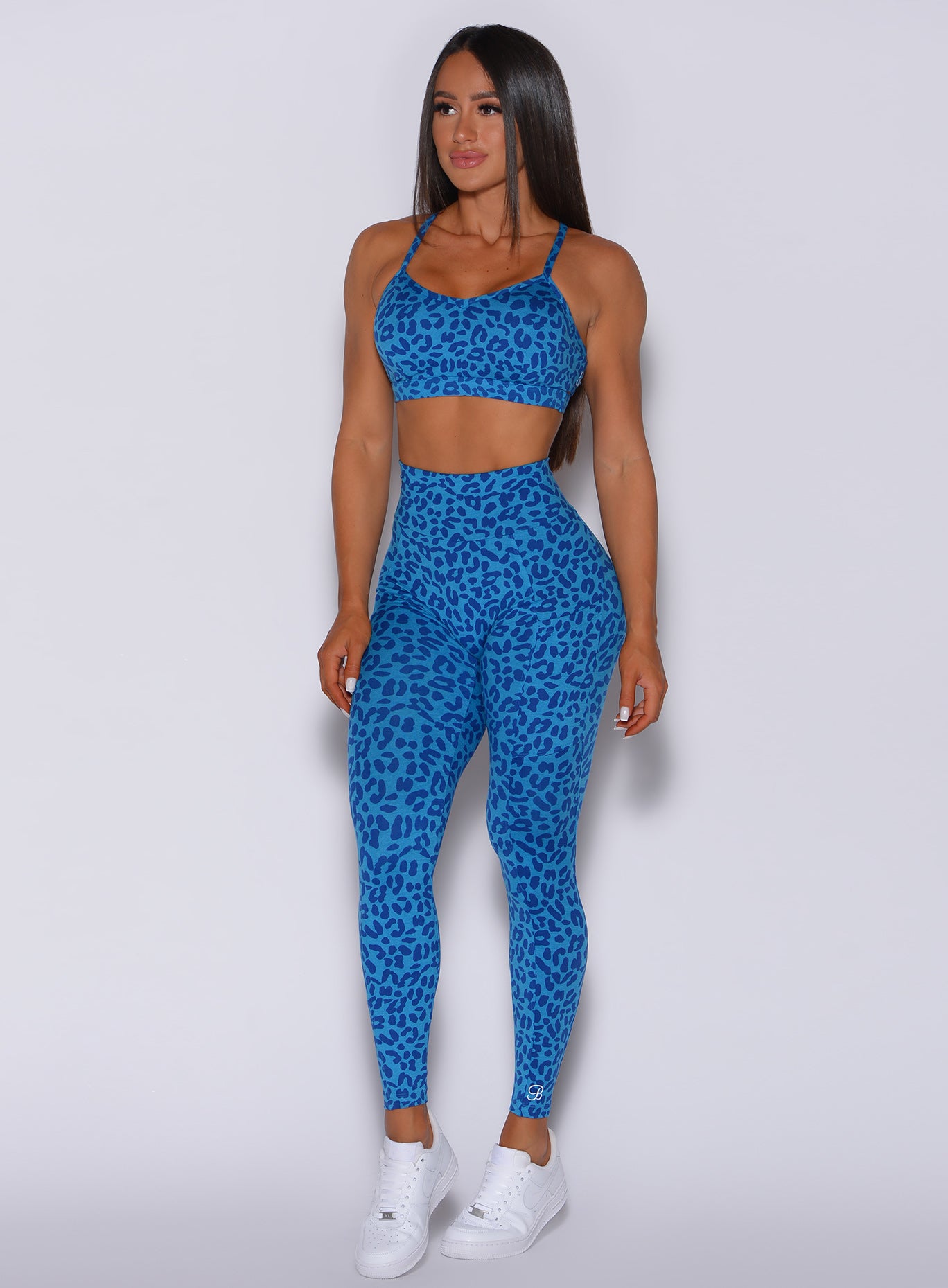 Front profile view of a model facing to her right wearing our curves leggings in blue cheetah color and a matching bra