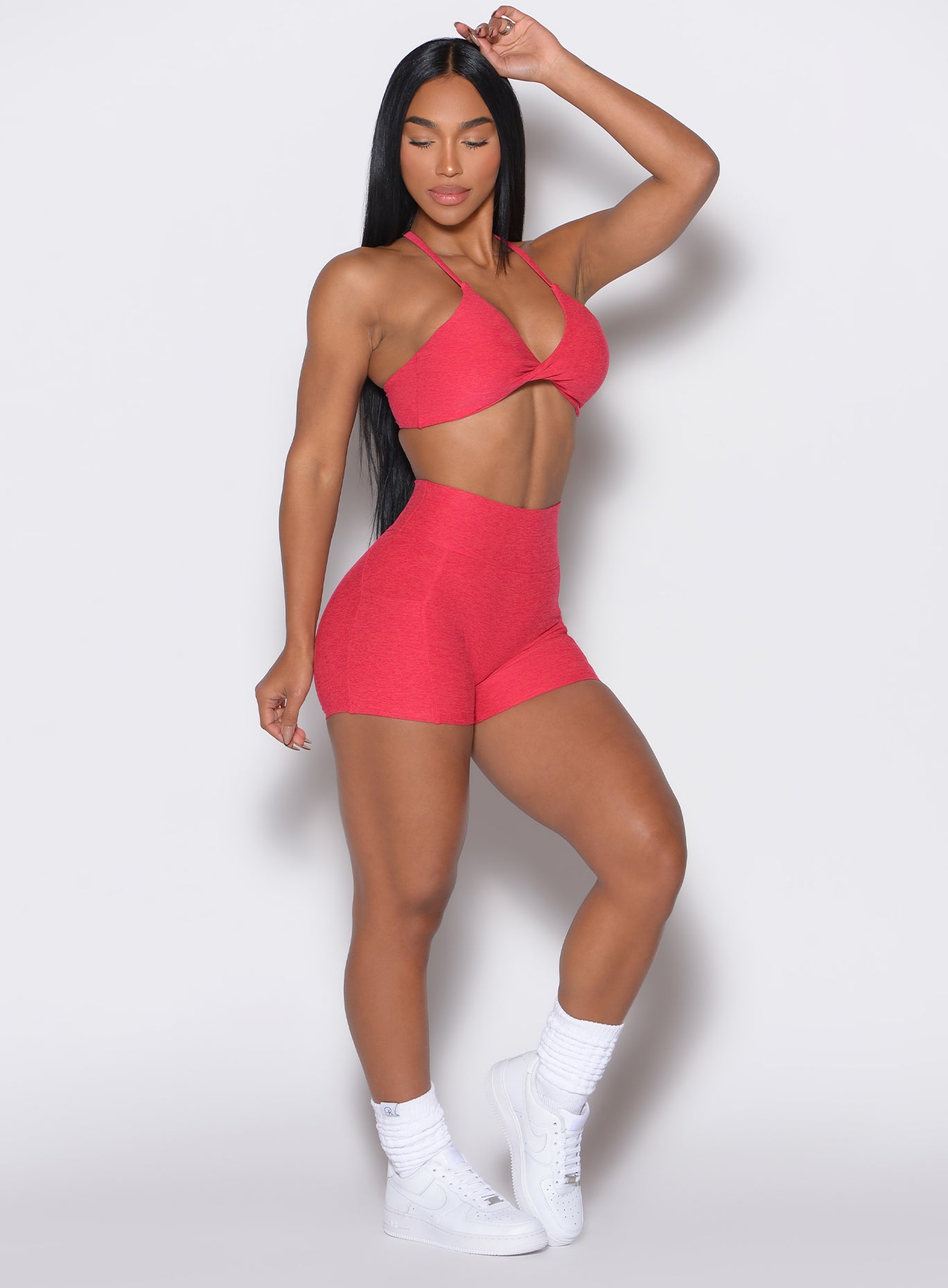 right side profile view of a model wearing our scrunch shorts in Raspberry Punch color along with a matching bra