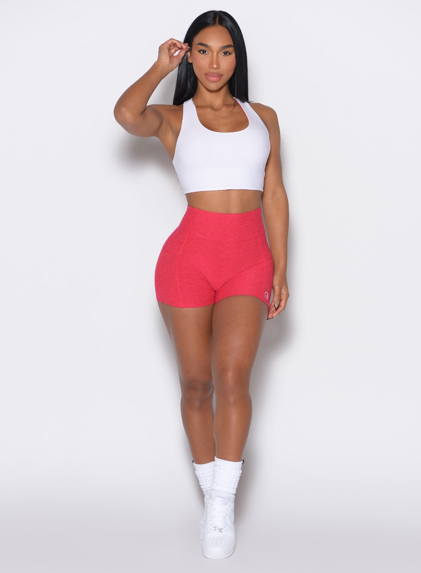 front profile view of a model wearing our scrunch shorts in Raspberry Punch color along with a white reversible bra