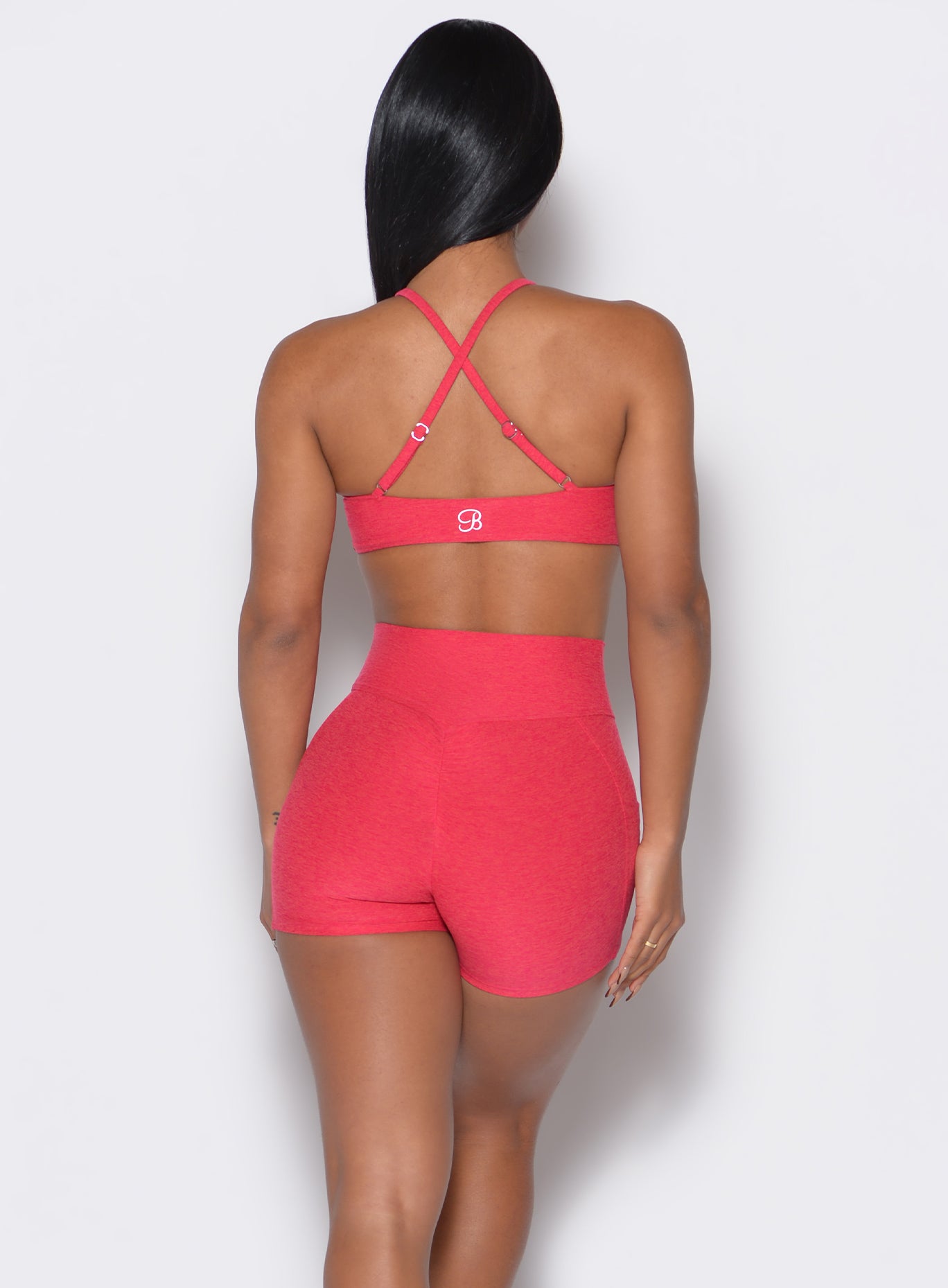 Back profile view of a model wearing our twist mini bra in Raspberry Punch color along with a matching shorts