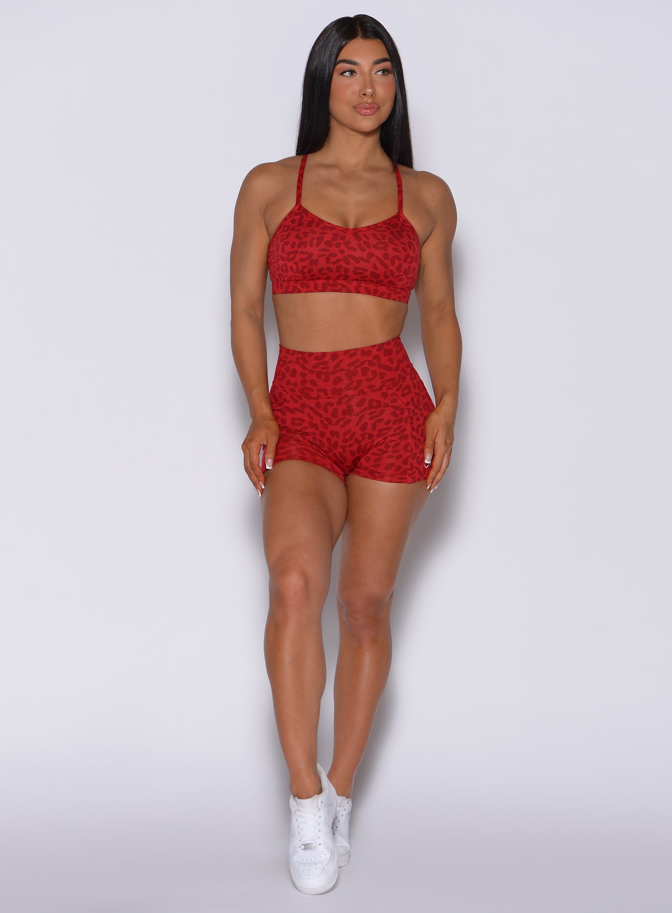 Front profile view of a model wearing our curves shorts in red cheetah color along with a matching bombshell sports bra