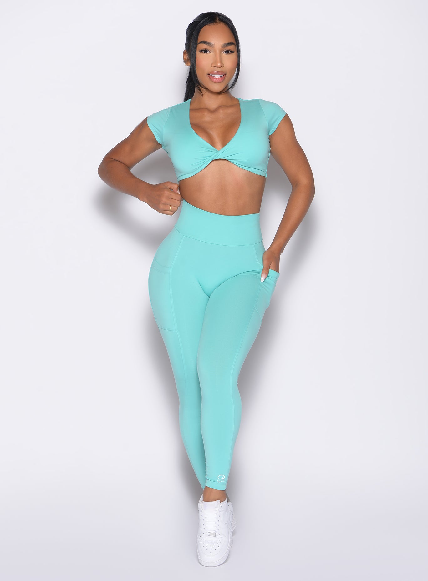 front profile view of a model with one hand inside the pocket of the leggings wearing the Define Leggings in Aquatic Awe color