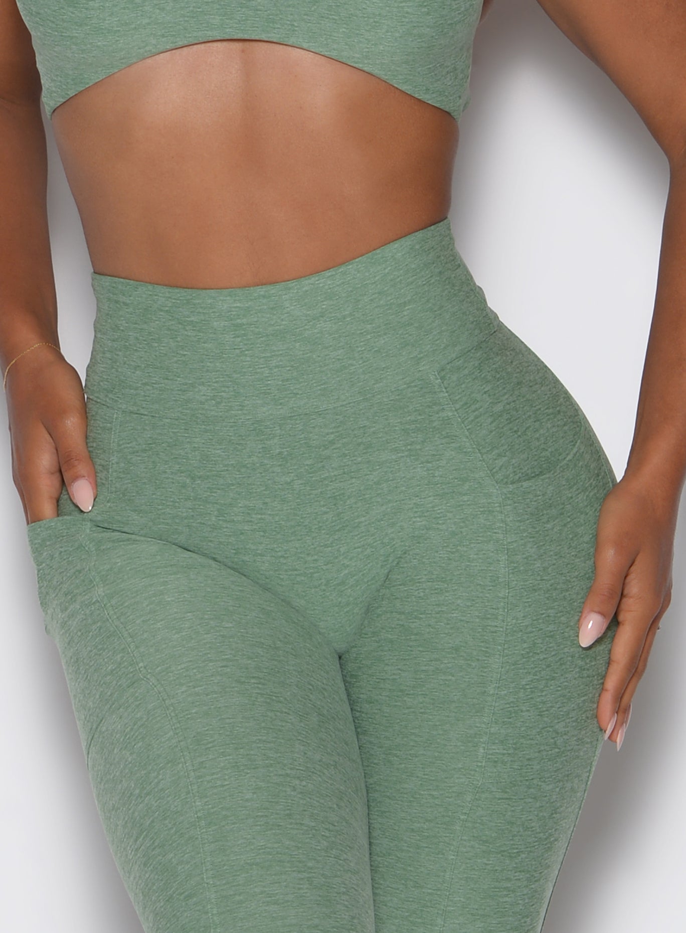 zoomed in front view of a model wearing the Define Leggings in basil color