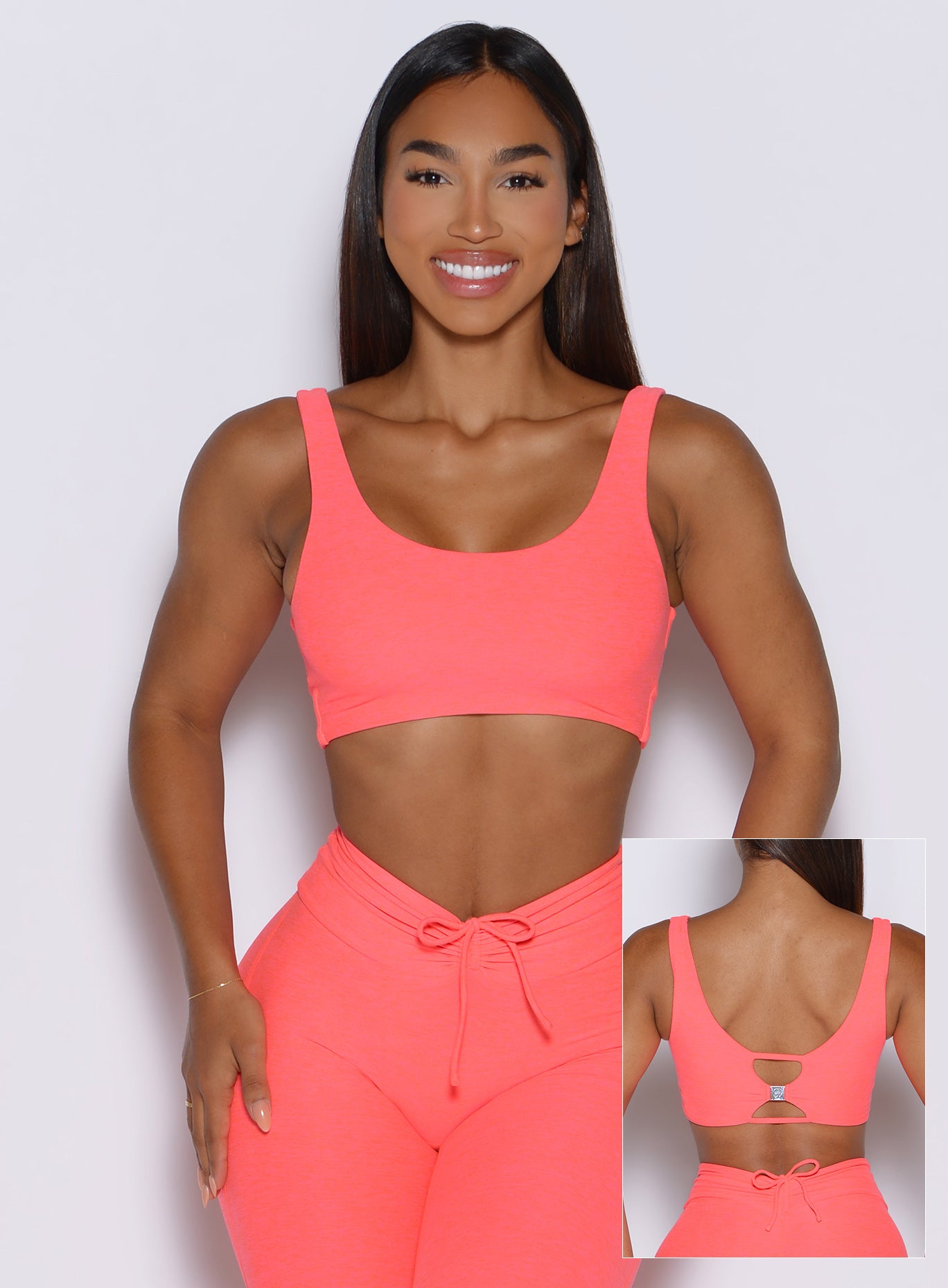 front profile view of a model highlighting the two way style of the Dualmode Bra in neon apricot pink color with the plain side in front and the B log on the back side