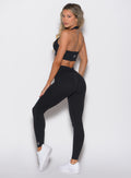 back left side profile view of a model looking over her shoulder wearing the Figure Butt Lift Leggings in black color