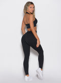 right side profile view of a model looking over her shoulder wearing the Figure Butt Lift Leggings in black color