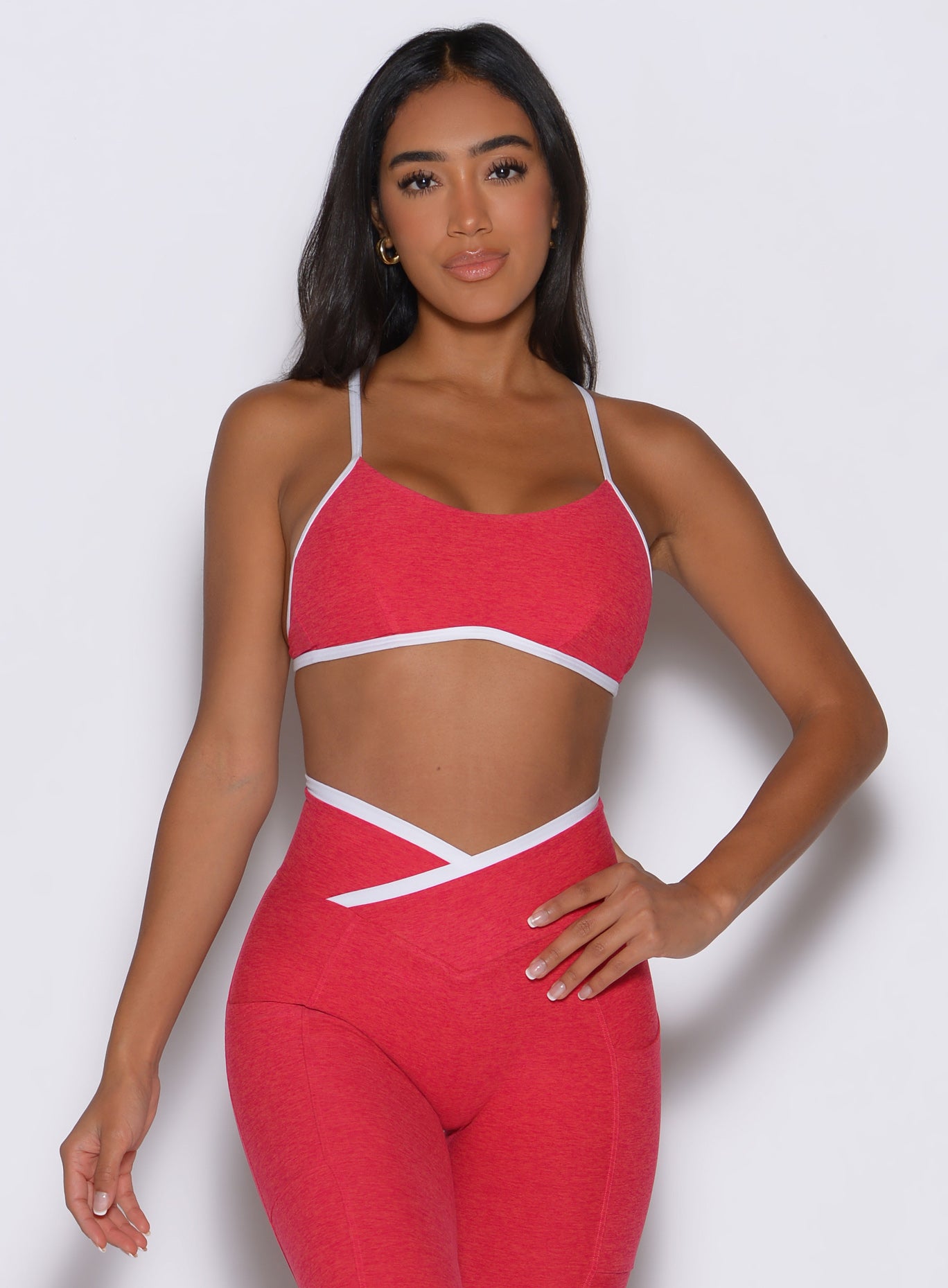 front profile view of a model with one hand on her waist wearing the Finish Line Bra in Raspberry Punch color