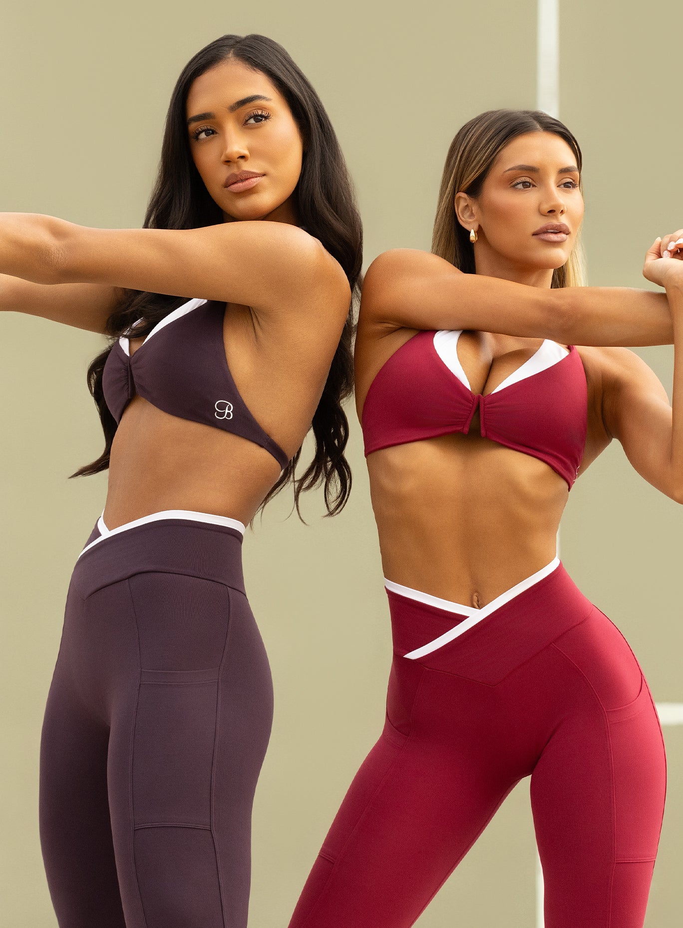 two models side by side in outdoors wearing the Contrast Voltage Sports Bra in maroon and black orchid color paired with the matching bottoms