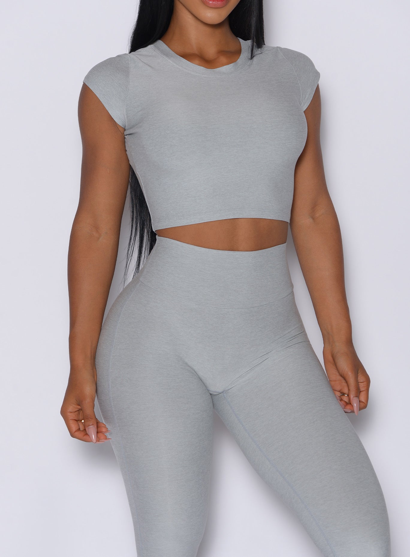 front profile view of a model facing forward wearing our fit fam active tee in light cloud color along with the matching leggings