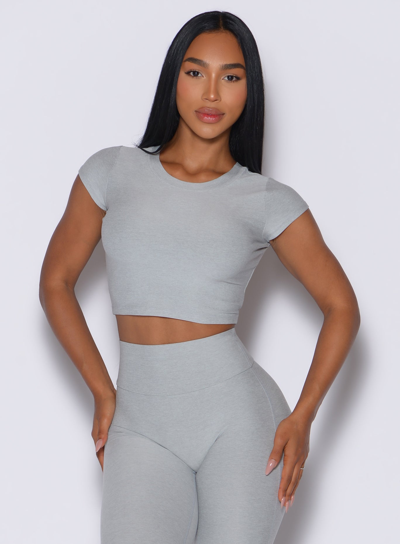 front profile view of a model wearing our fit fam active tee in light cloud color along with the matching leggings