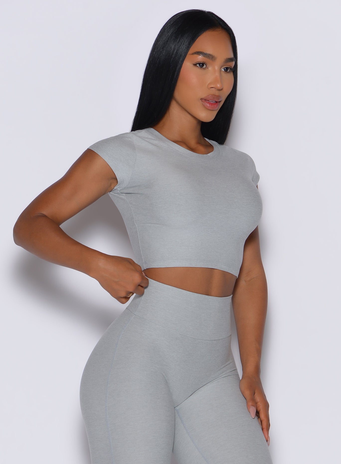 front profile view of a model angled slightly to her left wearing our fit fam active tee in light cloud color along with the matching leggings