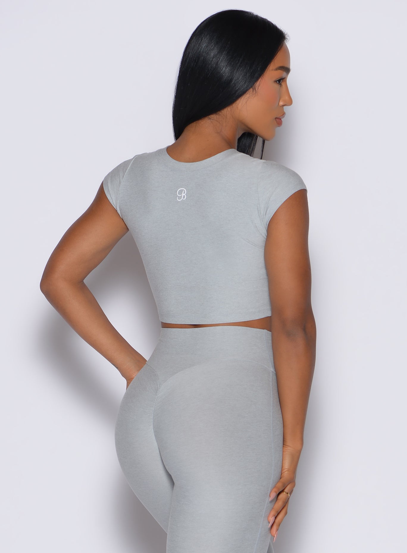 back profile picture of a model wearing our fit fam active tee in light cloud color along with the matching leggings