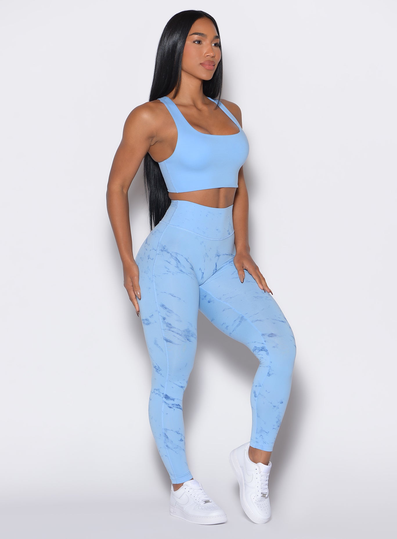 right side profile view of a model wearing our fit marble leggings in Blue Jay color along with a matching bra