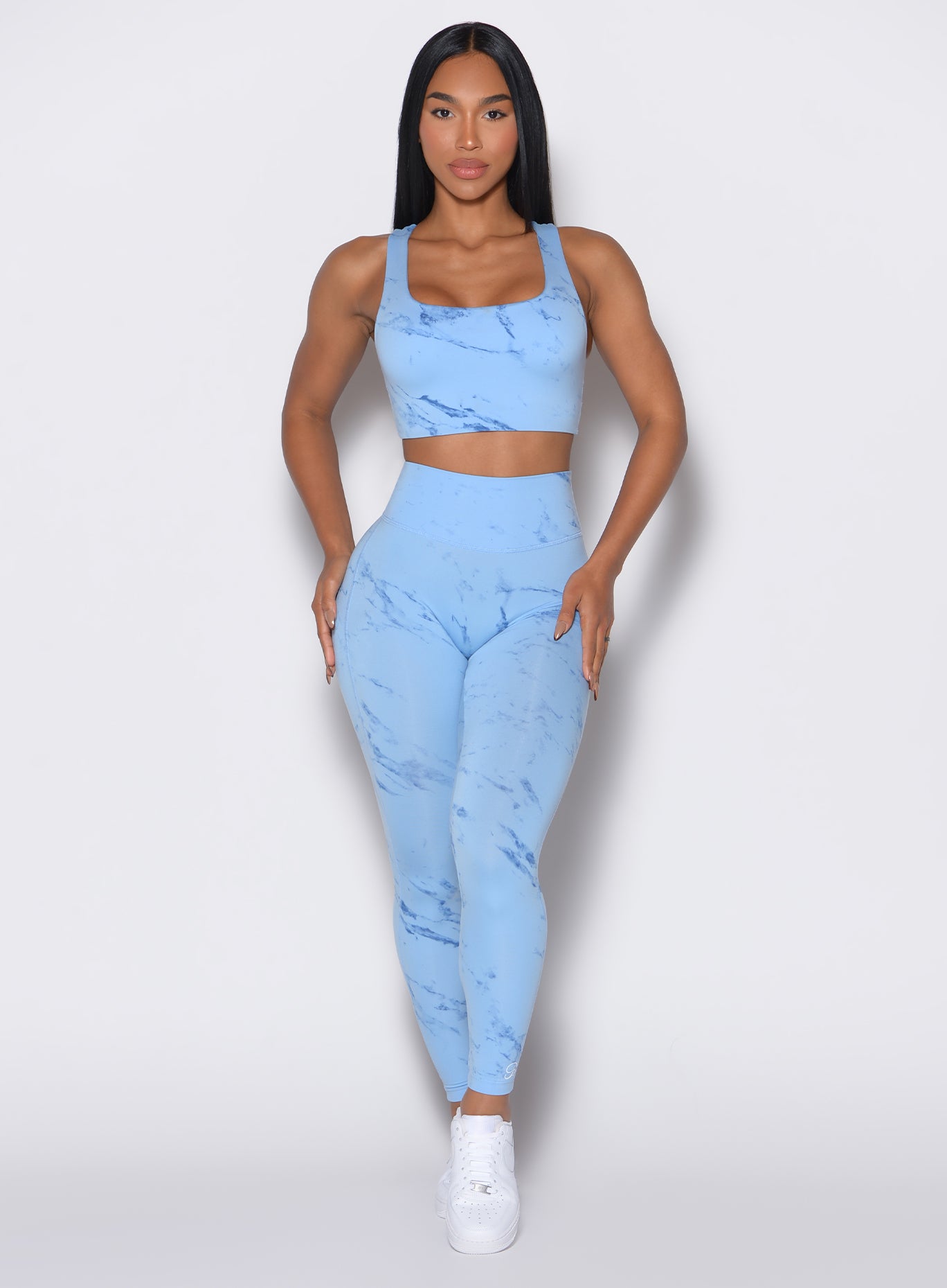 front profile view of a model wearing our fit marble leggings in Blue Jay color along with a matching sports bra