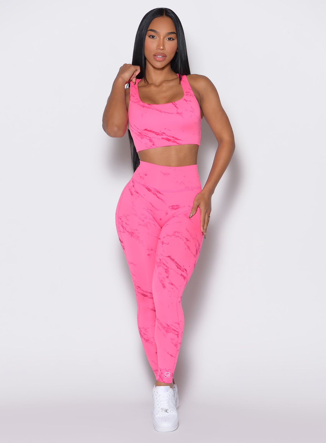 front profile view of a model wearing our fit marble leggings in Cotton Candy Skies color along with a matching sports bra