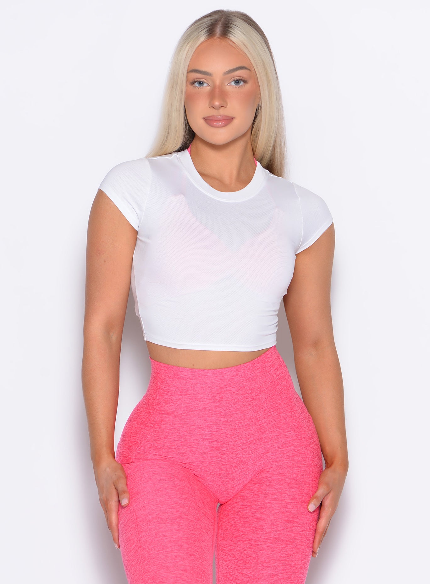 Model facing forward wearing our Flex Crop Tee in White color and the Curves 2.0 Leggings in Neon Flame color