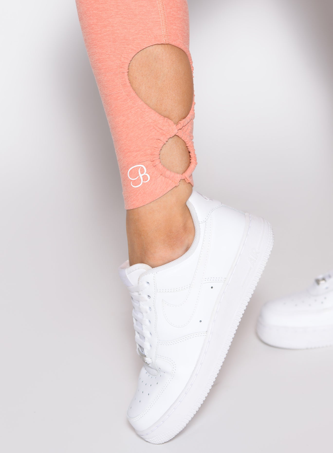 Coral Peach Form Flex Leggings featuring detailed ankle keyhole cutouts and a sculpting fit.